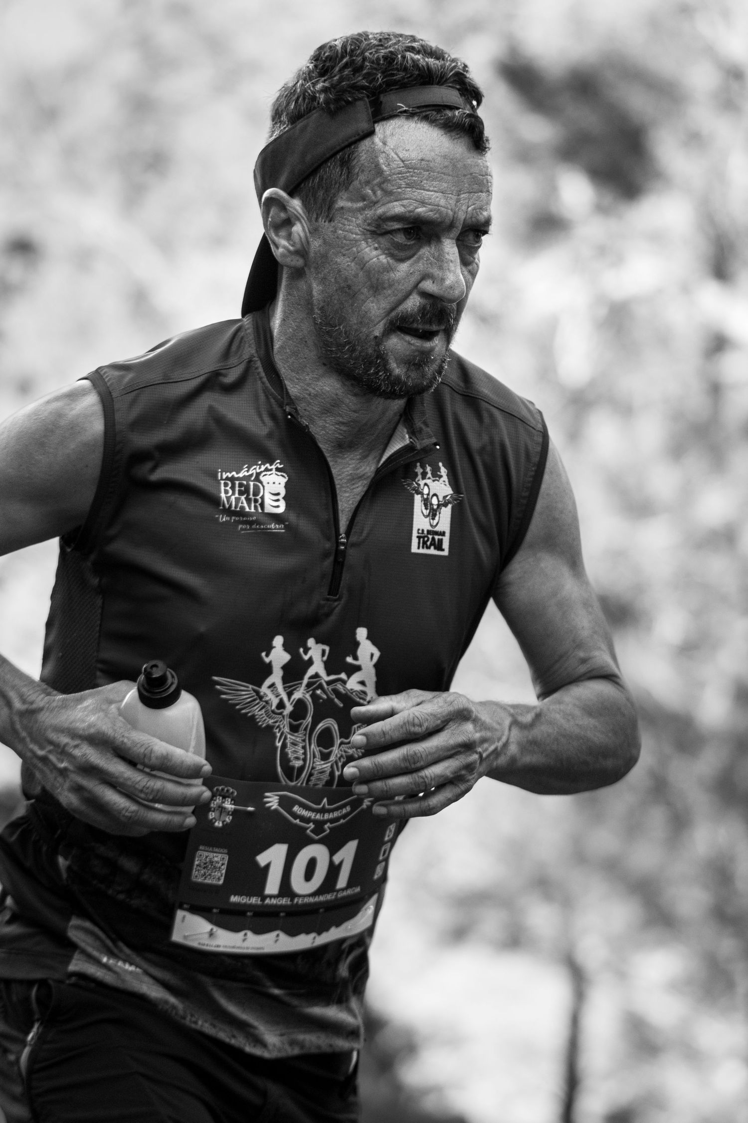 Retrato potente en blanco y negro de un corredor con gesto de esfuerzo durante la carrera CxM Rompealbarcas. Fotografía deportiva emotiva.