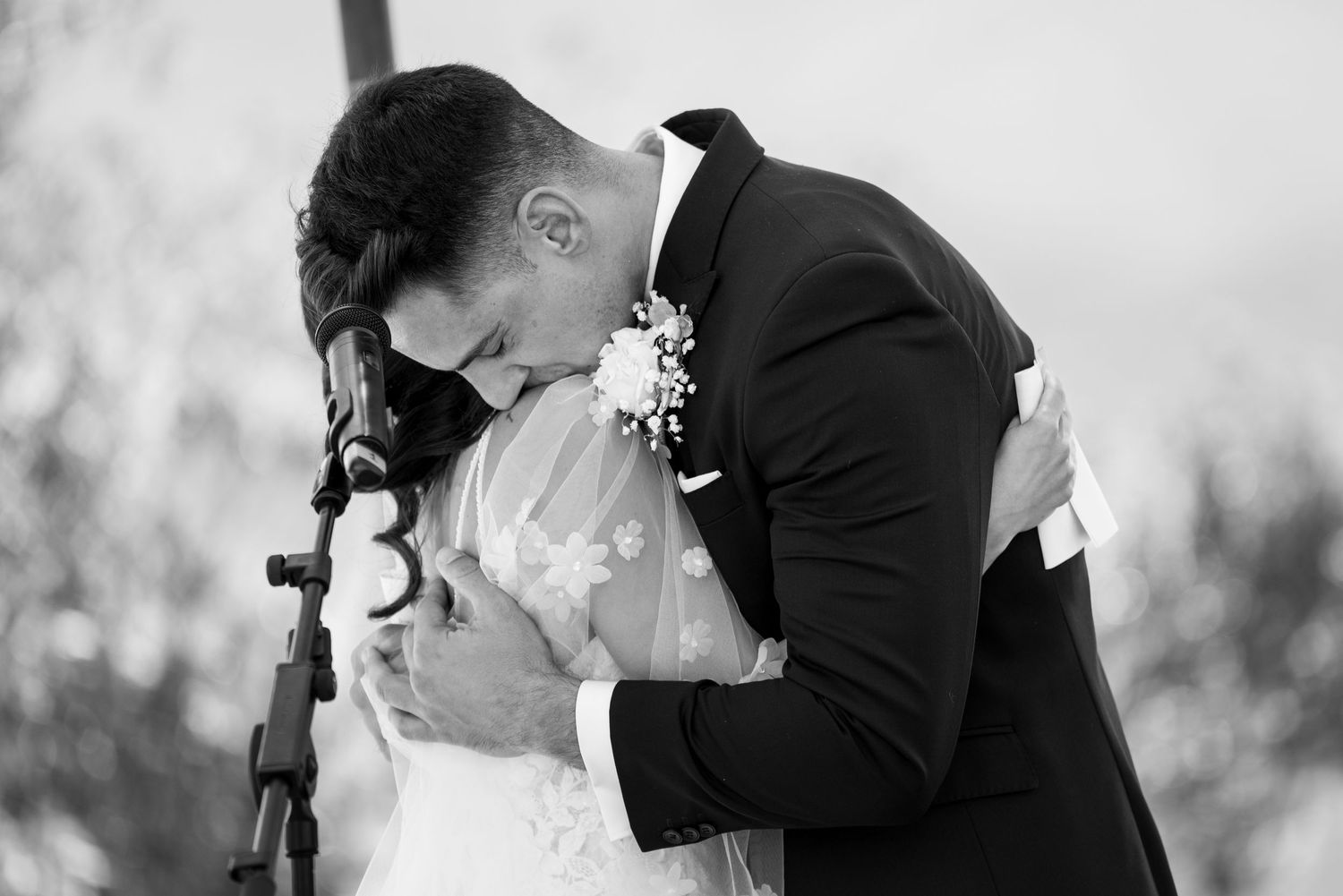 Emotivo abrazo de una pareja de novios capturado en blanco y negro. Fotografía documental y auténtica de un momento íntimo de boda.