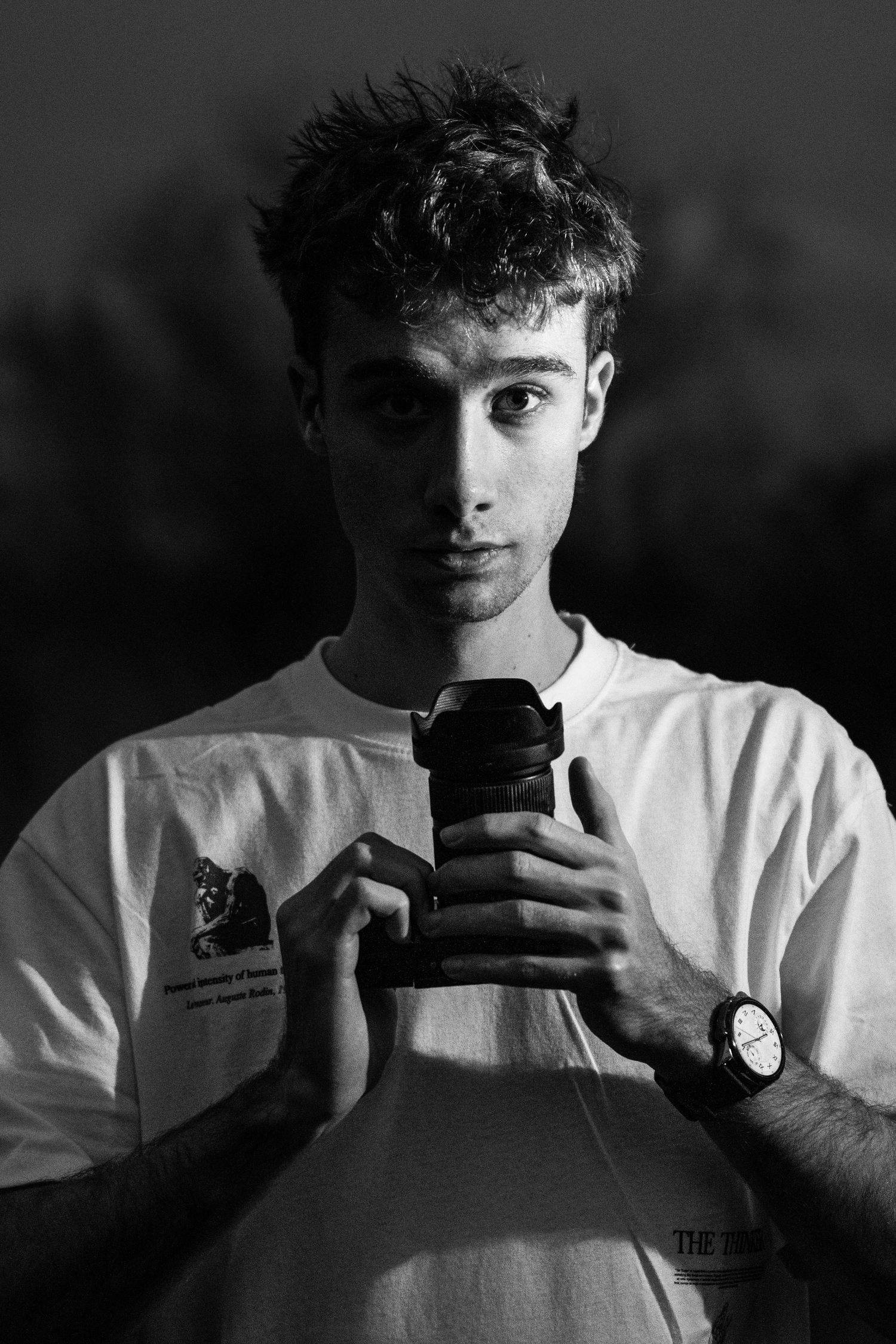 Retrato artístico en blanco y negro del fotógrafo de autor Guillermo ARW mirando a cámara y sujetando su equipo. Imagen de marca personal.