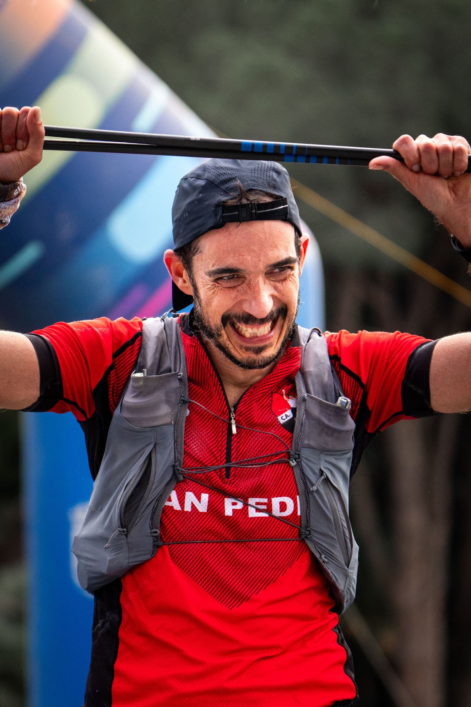 Corredor de trail running muy emocionado celebrando al cruzar la línea de meta. Fotografía deportiva documental de final de carrera.