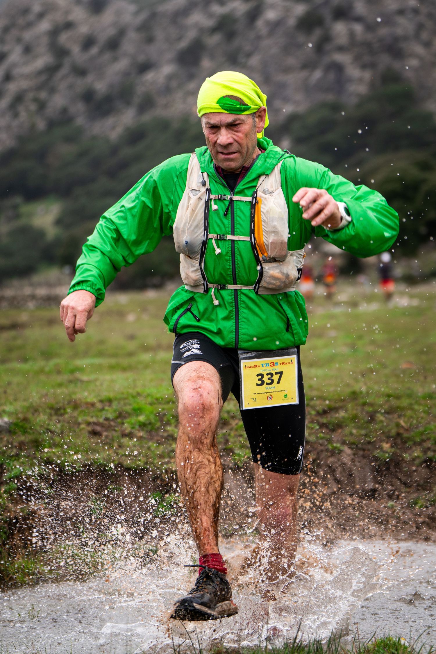 Corredor de trail cruzando un charco de agua y salpicando en la carrera Jimera3Trails. Fotografía de acción deportiva en naturaleza.