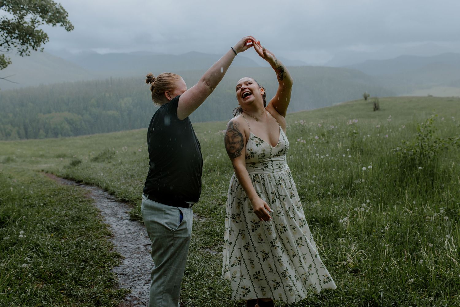 A joyful couple dancing together in a rainy green mountain meadow, one spinning the other.