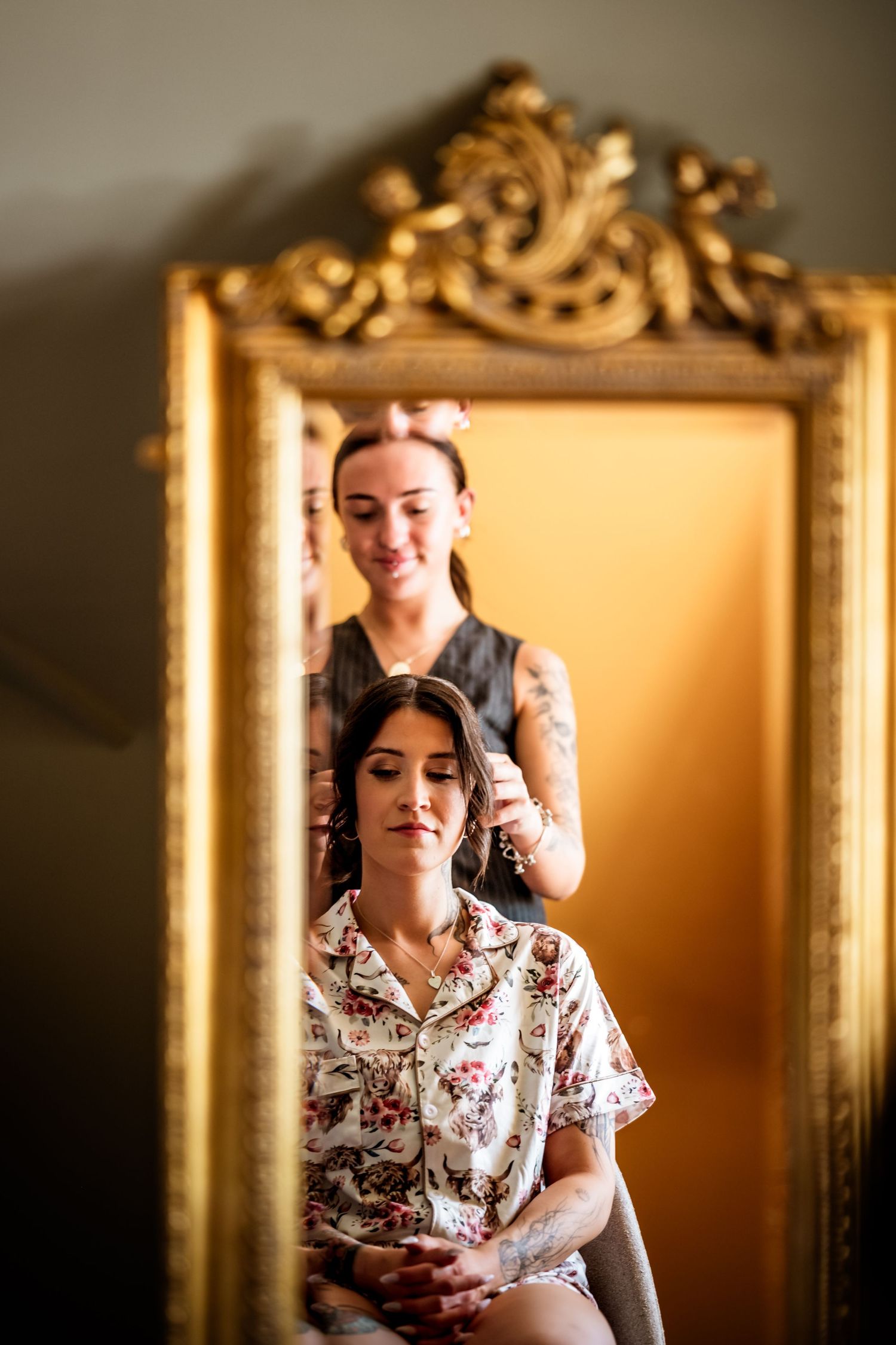 Reflection in ornate gold mirror shows wedding preparation scene with vintage decor.