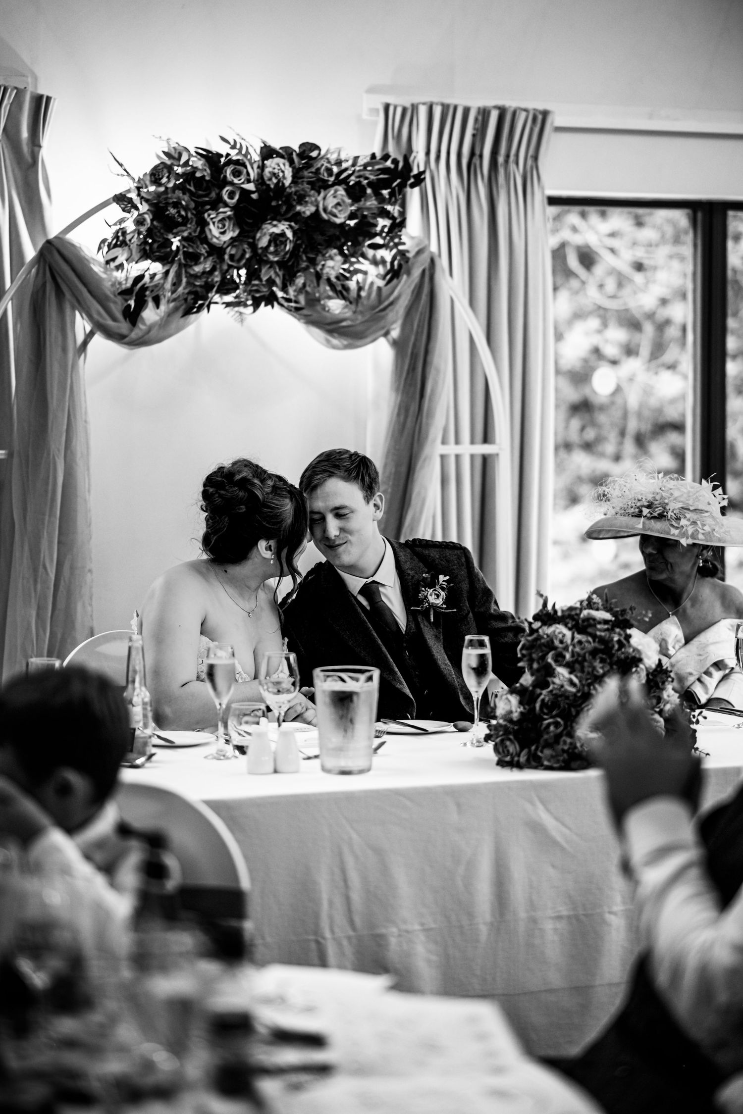 Black and white photo of a wedding reception dinner with elegant table settings and floral centerpieces. LochNess CountryHouse Hotel Wedding