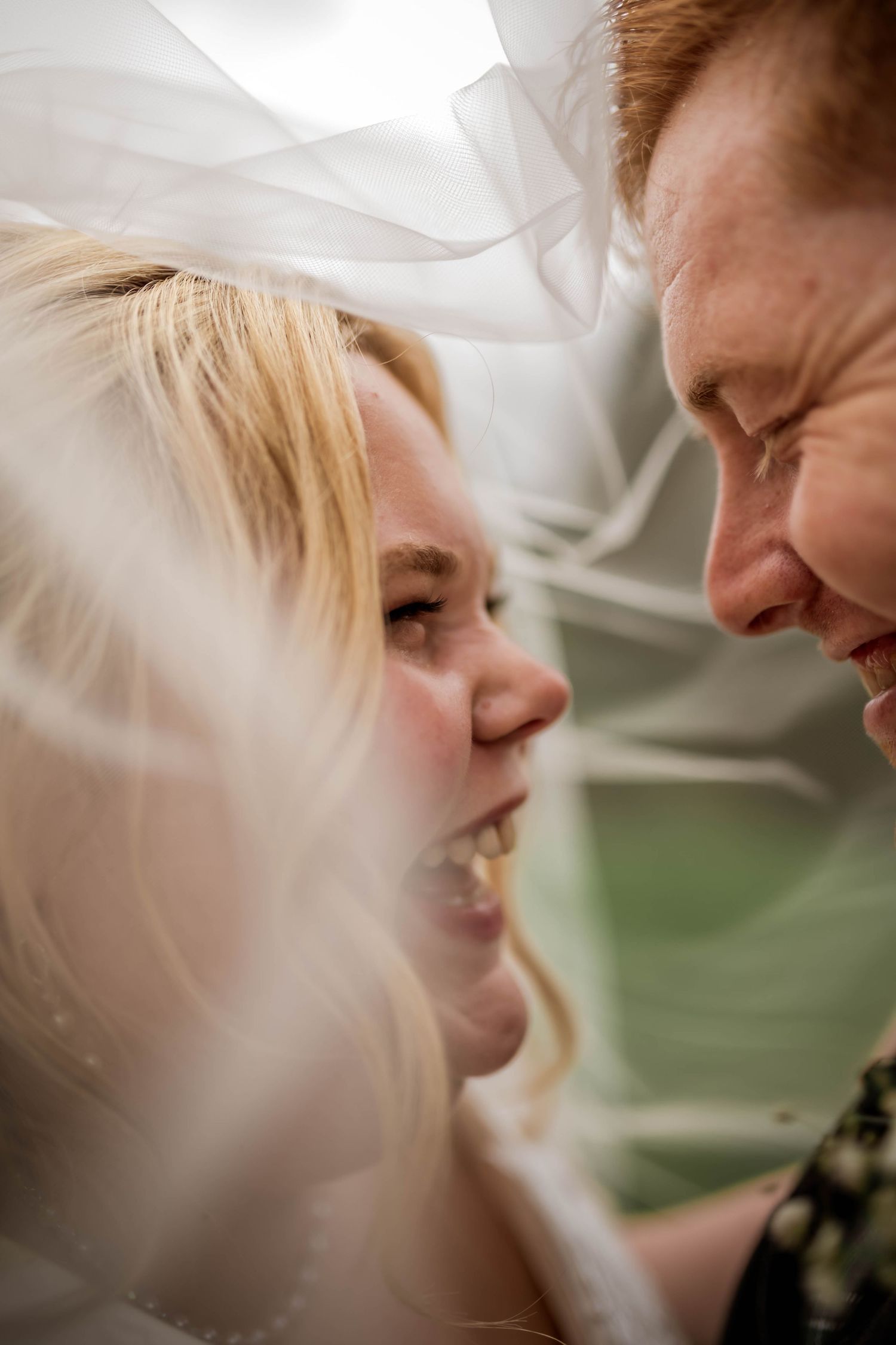 An intimate moment captured through delicate white wedding veil fabric.