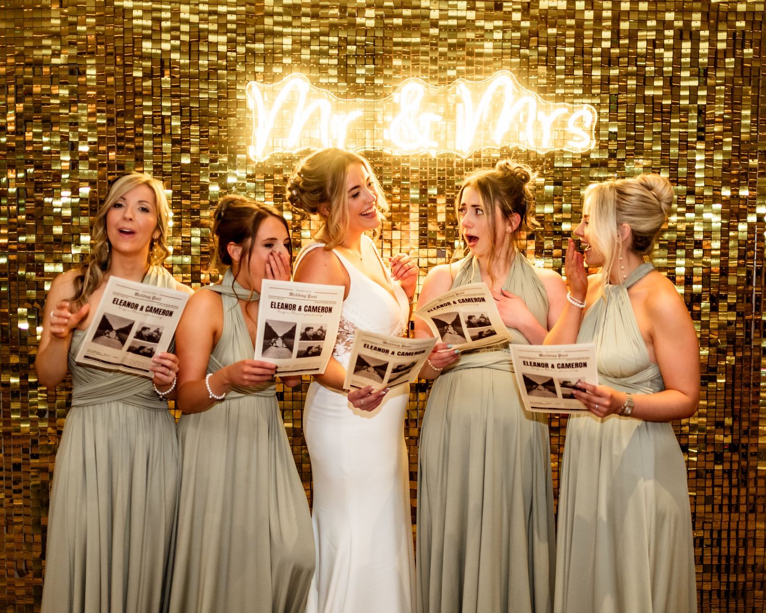 Wedding party in sage green dresses poses against a golden sparkly backdrop. Drumossie Hotel Wedding Photography