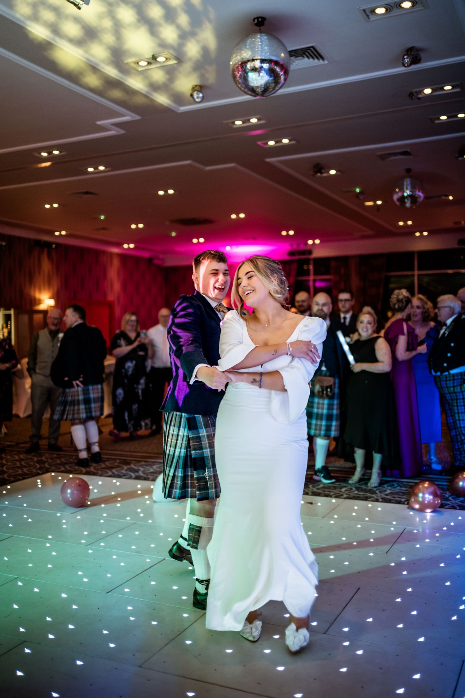 Wedding reception dance floor illuminated with colorful lights and disco effects. Drumossie Hotel Wedding Photography