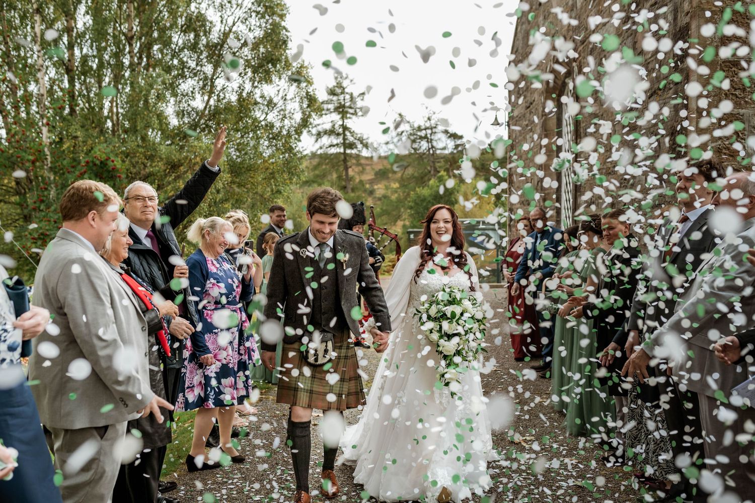 Wedding celebration with confetti being thrown over the newlyweds in a joyful outdoor ceremony.