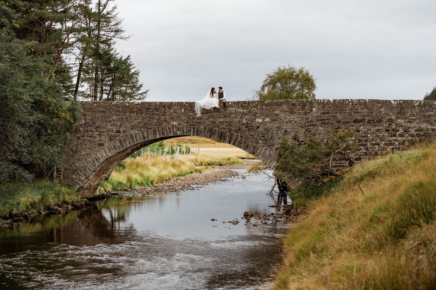 Stone bridge in Scottish countryside with couple in distance. Scottish Highlands Achnasheen Wedding photography