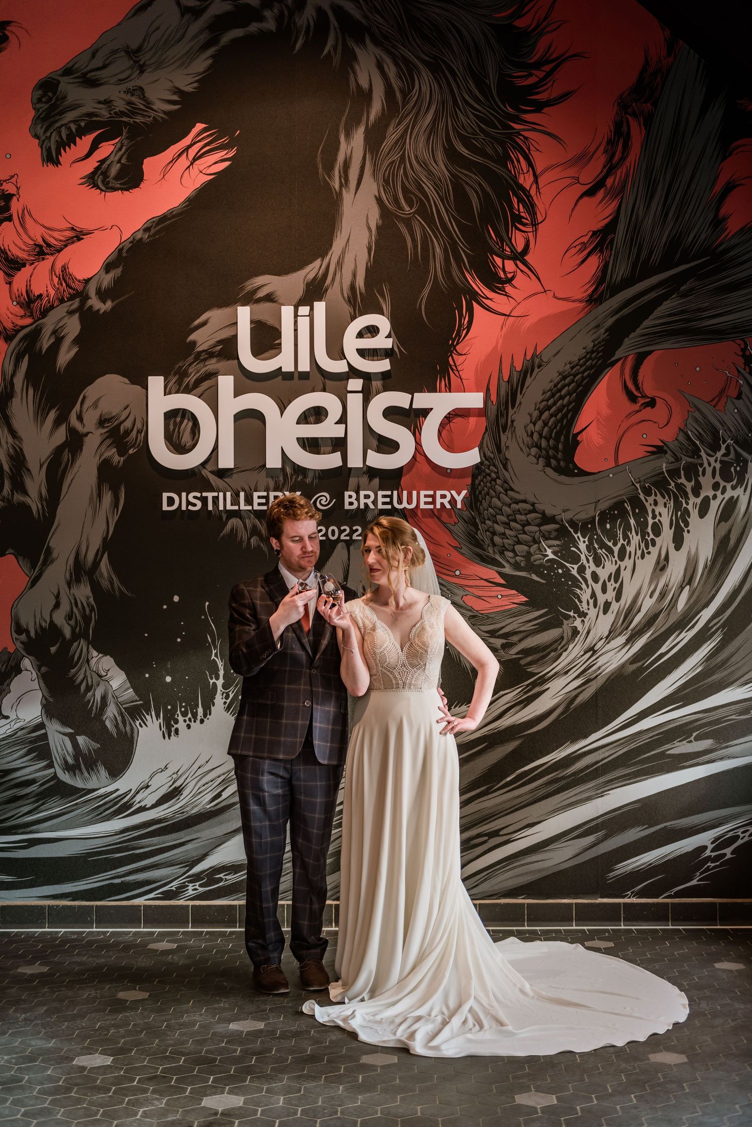 A wedding couple poses against dramatic brewery mural featuring a dark horse design.