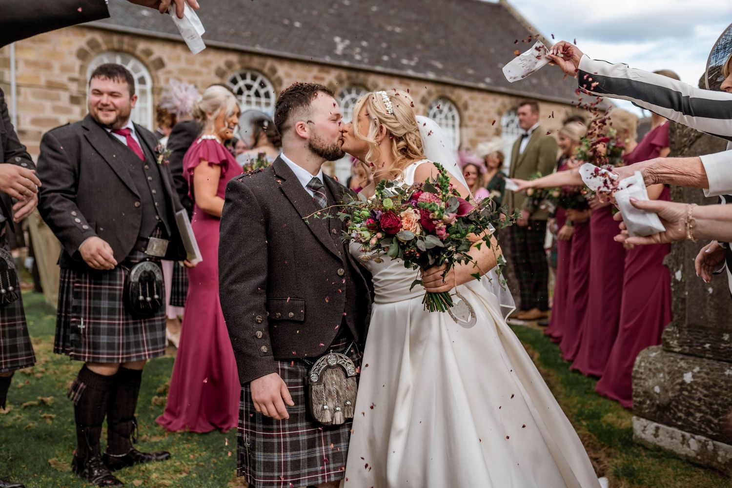 Guests throwing confetti at newlyweds during Scottish wedding celebration.