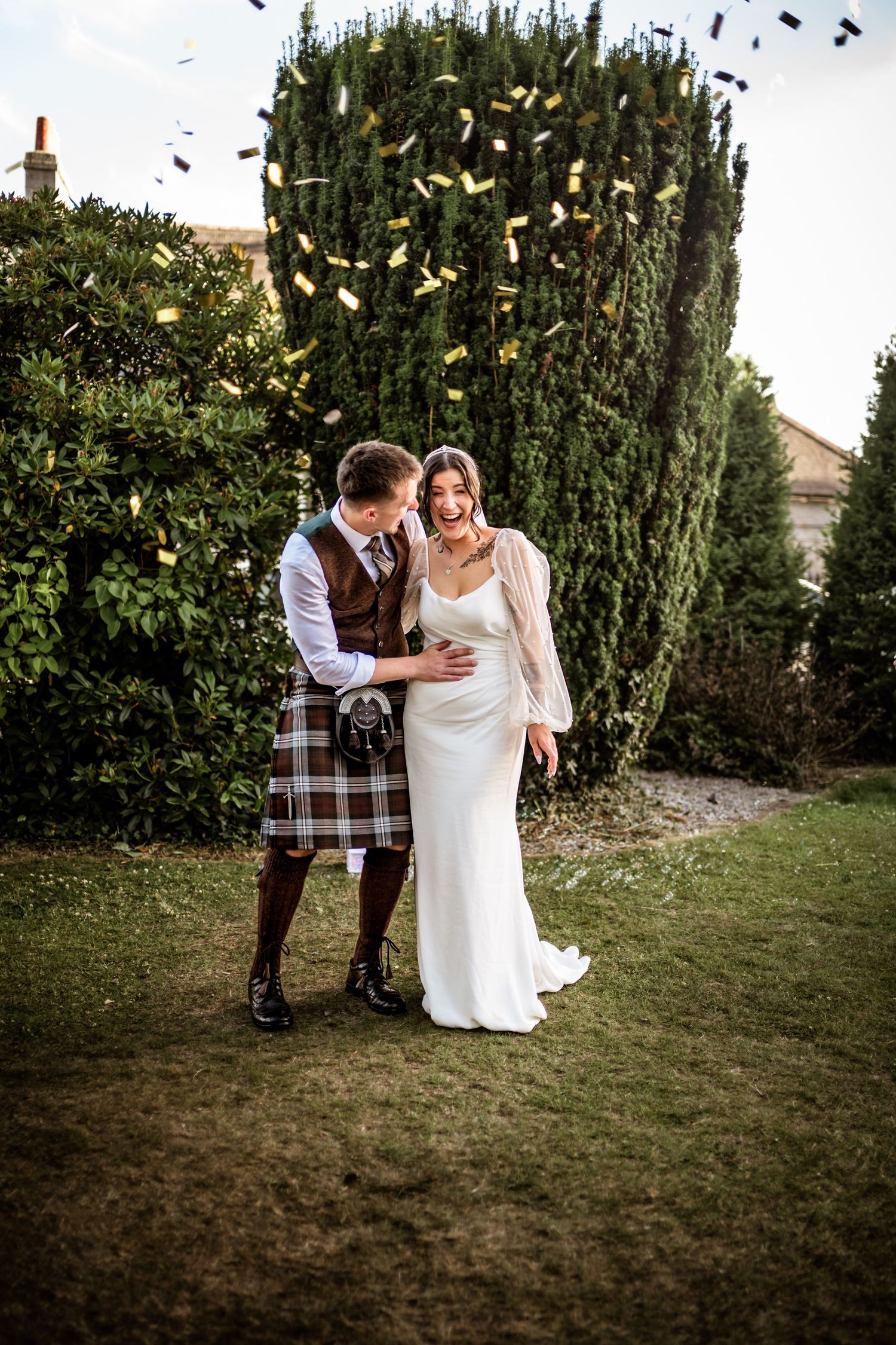 Newlyweds celebrating with confetti in a garden setting.Scottish Highlands  Wedding photography