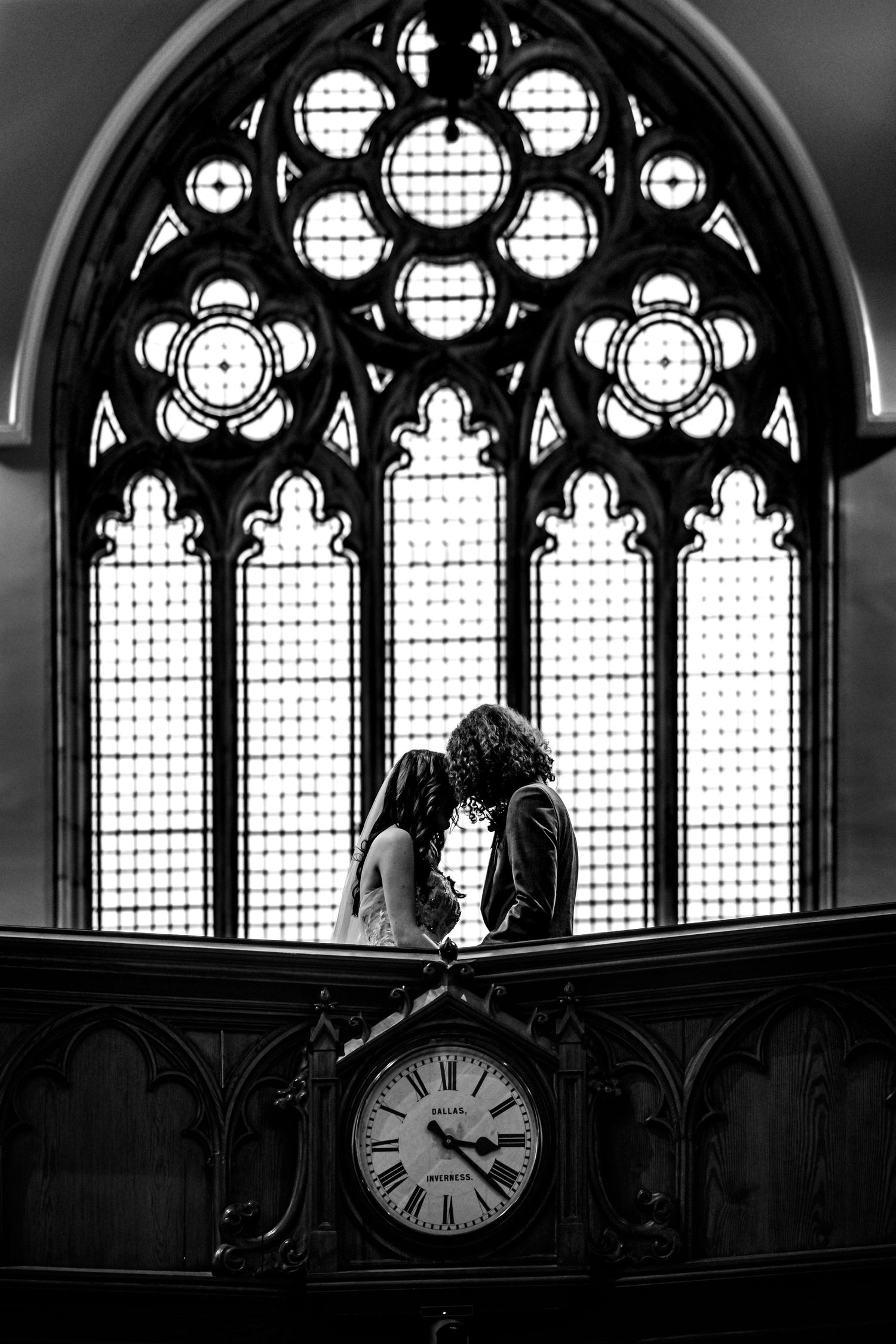 Gothic church windows with ornate stained glass and large clock create dramatic wedding backdrop. Inverness Church Wedding Photography