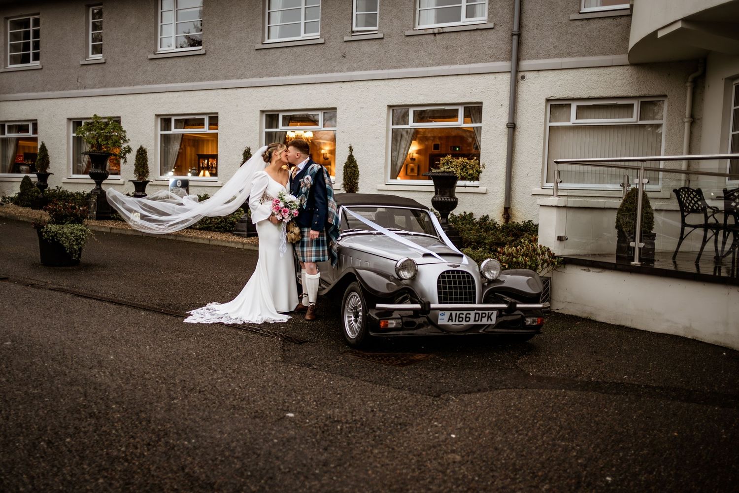 Classic wedding cars parked outside a stone building with elegant architecture.