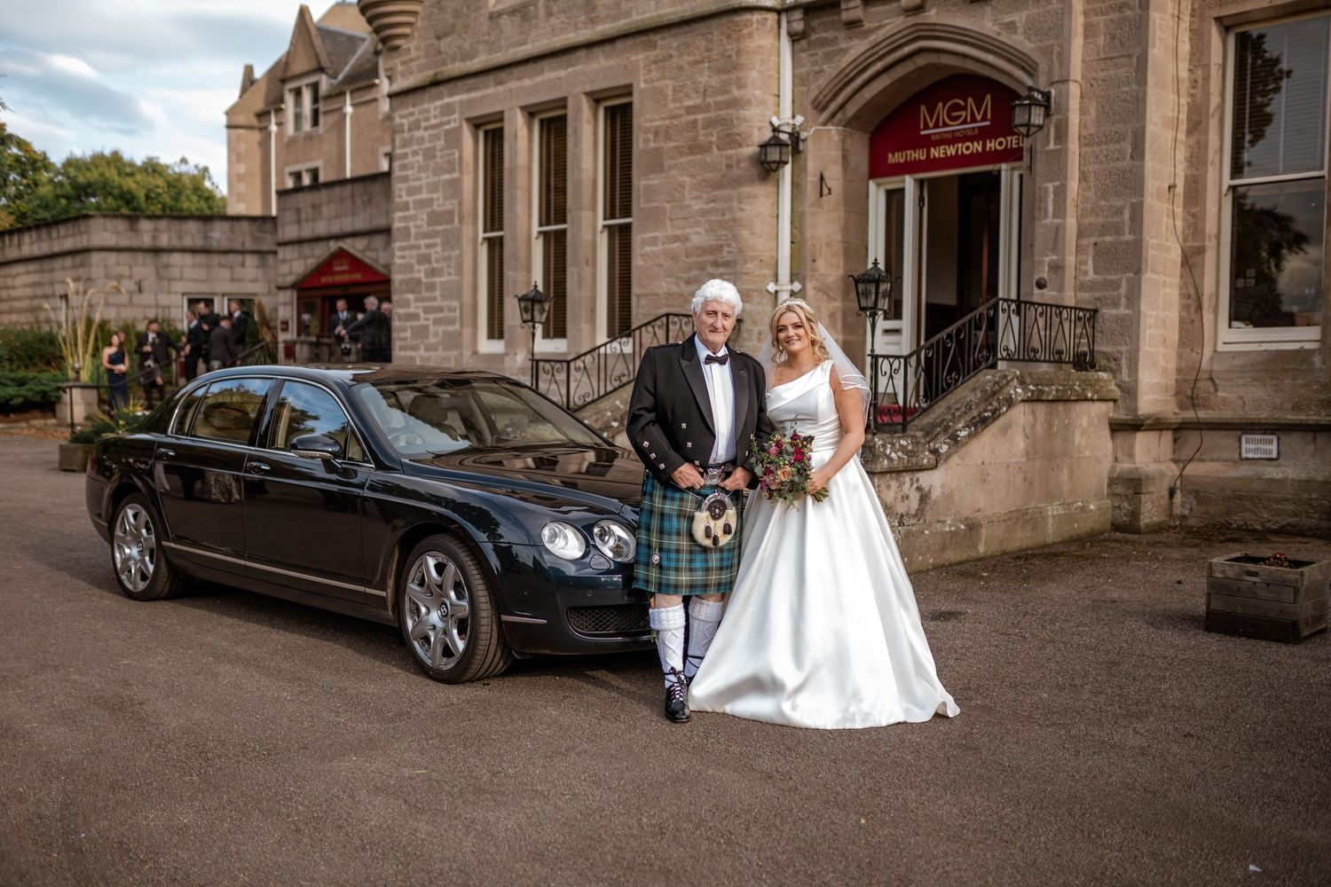 Classic wedding cars parked outside stone church building.