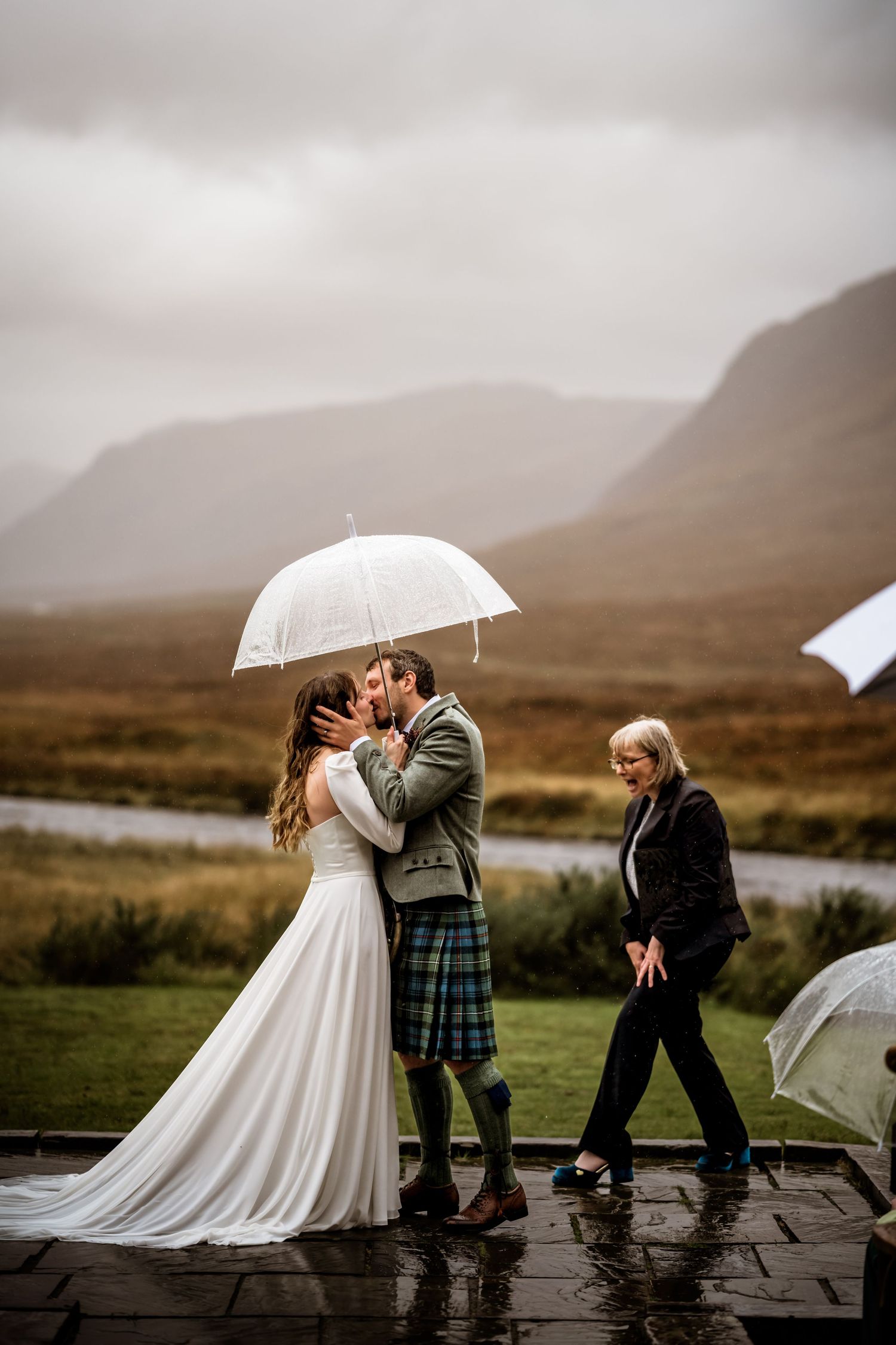A romantic rainy day wedding photo in the Scottish highlands with mountains in the background. Kingshouse Hotel Wedding Photography