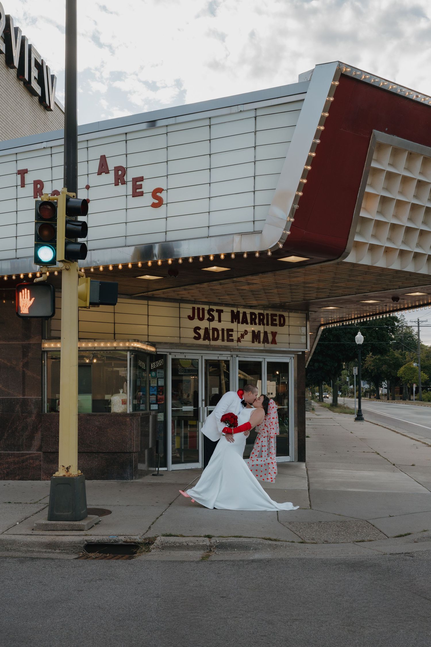 Bride and groom kiss under vintage theater marquee reading Just Married Sadie and Max outside the Riverview Theater in Minneapolis, MN.