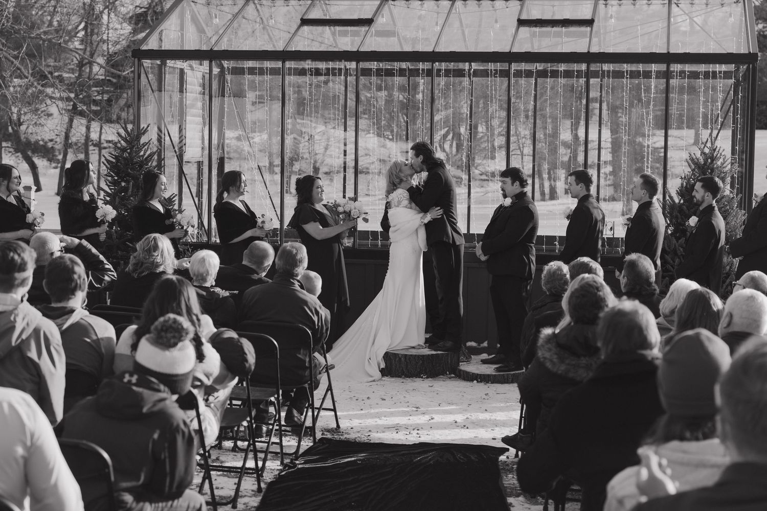 Black and white wedding ceremony outdoors with bride and groom at altar surrounded by guests seated in chairs in Minnesota during the winter