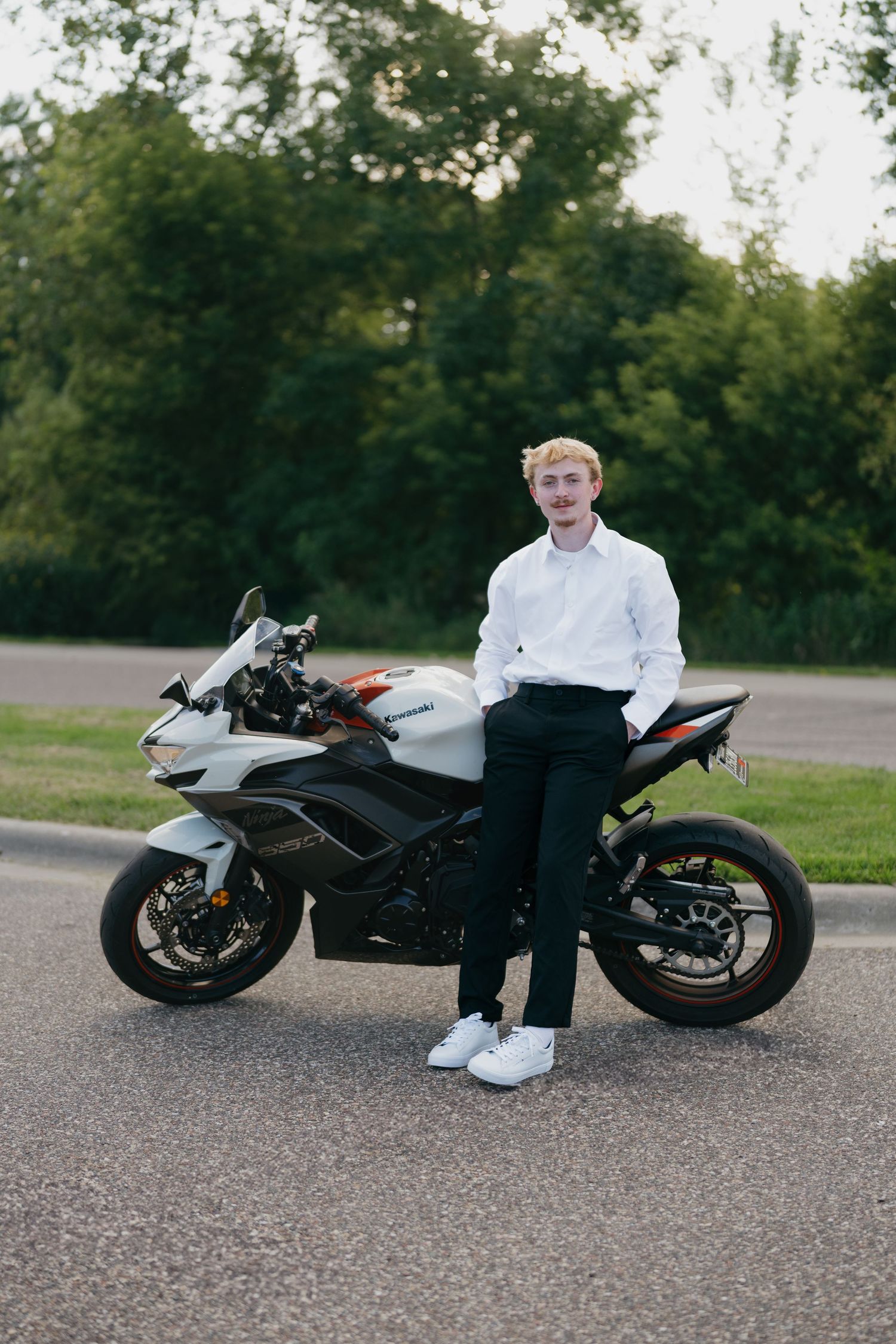 Young man posing confidently beside a sport motorcycle for his senior photo session at Lebanon Hills Regional Park in Eagan, Minnesota.