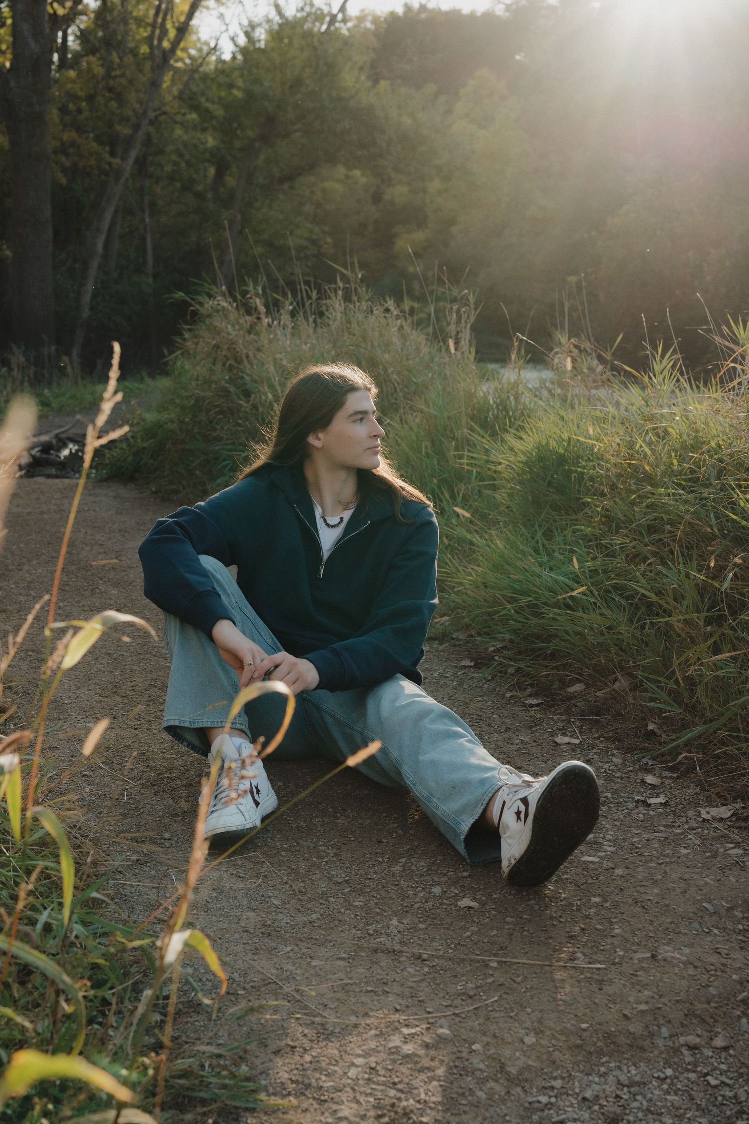 Young person sitting on a dirt path in golden sunset light surrounded by nature in Minnesota.