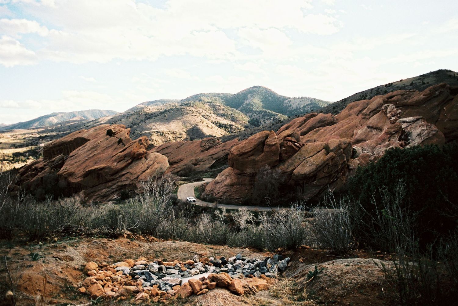 Scenic red rock canyon landscape with a winding road cutting through rugged Colorado mountain terrain.