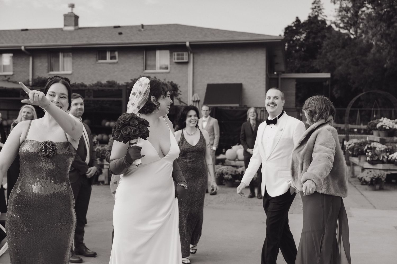 Black and white photo of bride and groom celebrating with wedding party guests in outdoor fall setting at Mother Earth Gardens in Minnesota.