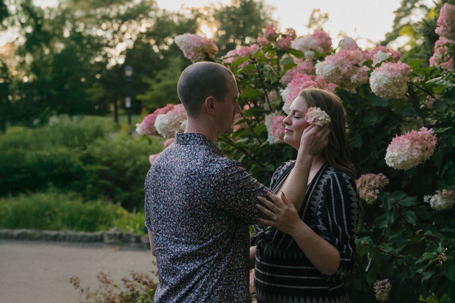 A couple shares a tender moment among blooming pink and white hydrangea bushes at sunset at Como Conservatory in St. Paul, Minnesota.