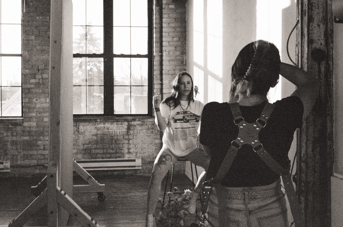 Black and white photo of a photographer shooting a model in a rustic brick studio with large windows in a studio in Minneapolis, Minnesota.