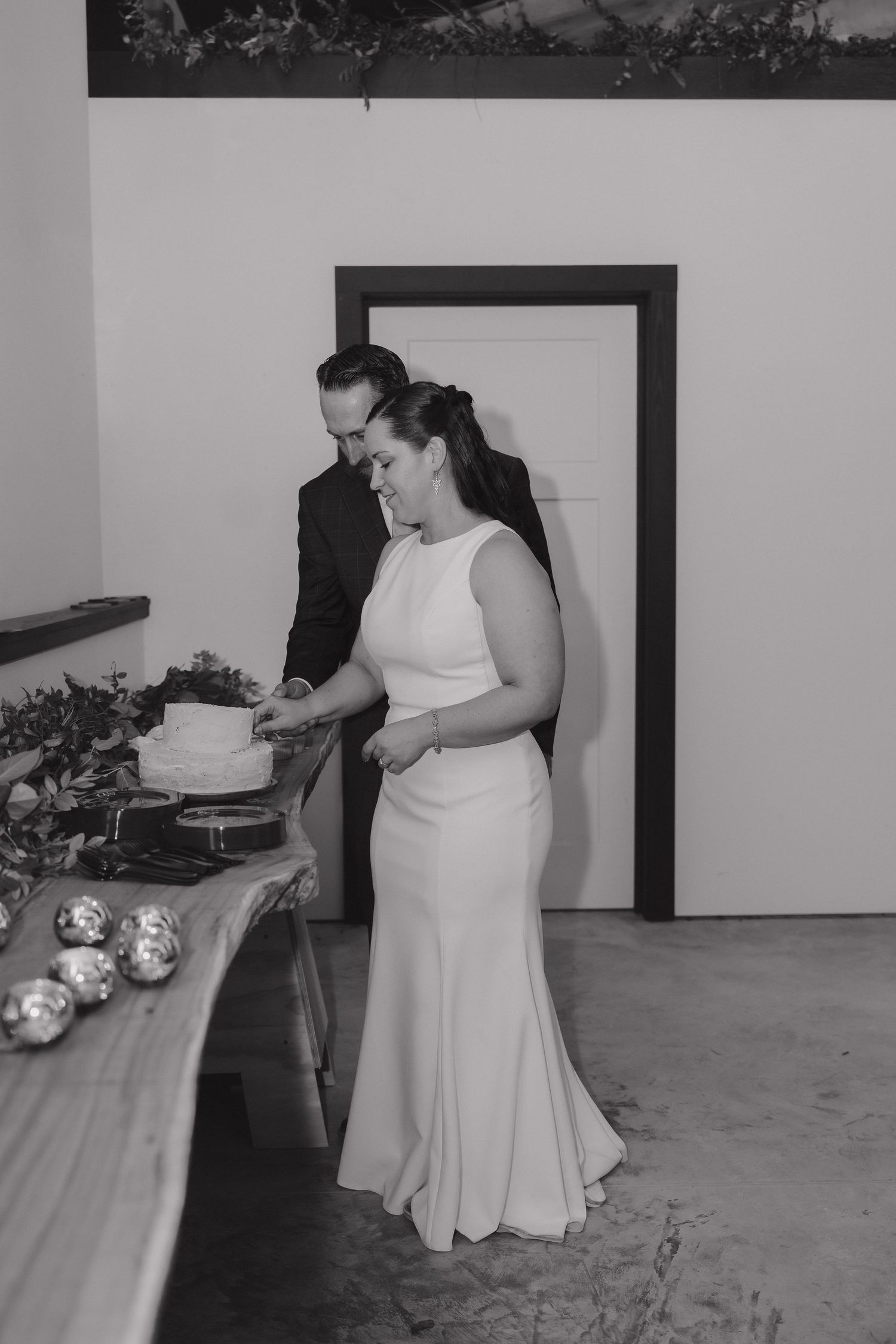 Black and white photo of bride and groom cutting their wedding cake at an elegant indoor reception in Southern Minnesota.