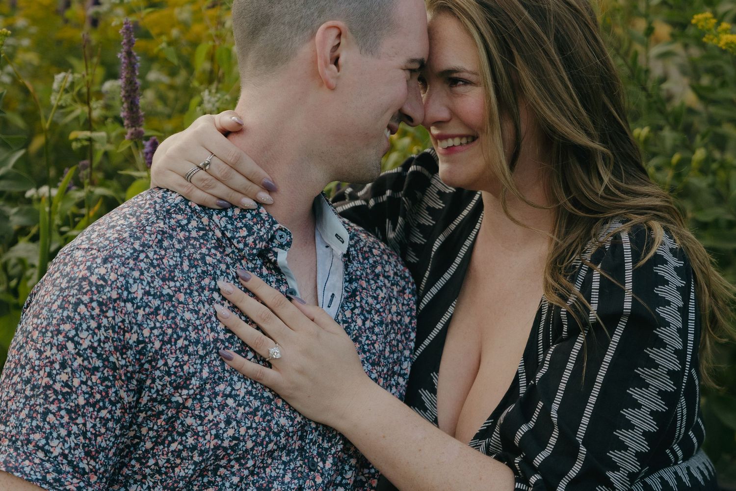 Happy couple embraces closely in a vibrant yellow wildflower field during a romantic engagement session in St. Paul, Minnesota.