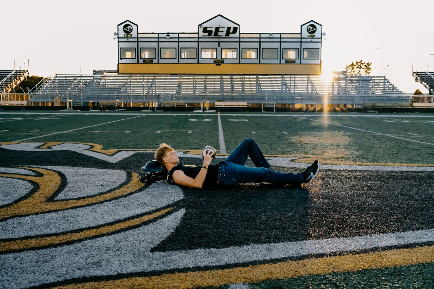 Teen poses on football field at SEP stadium during golden hour sunset photography session.