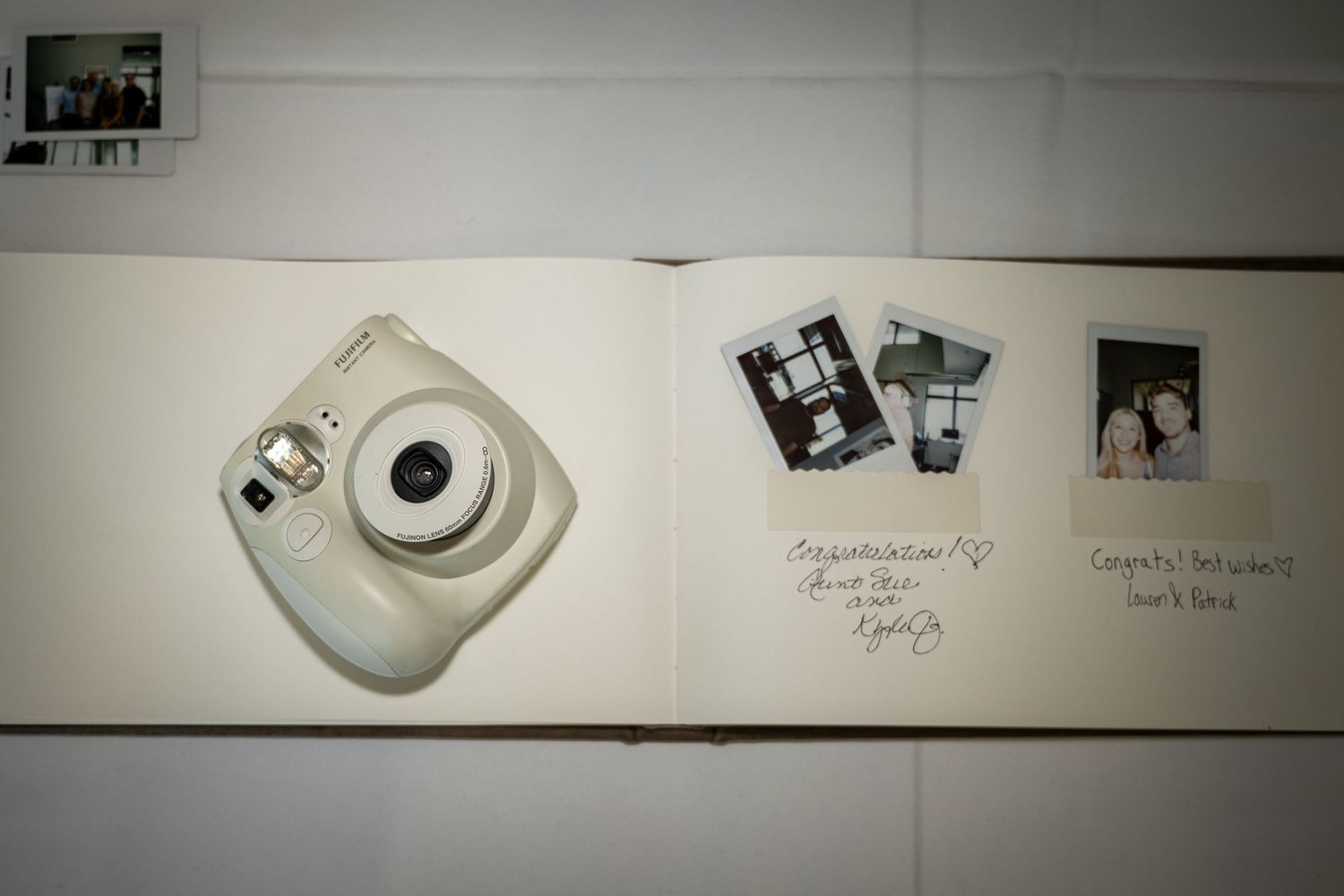 Open wedding guest book with Instax mini camera and Polaroid photos with handwritten congratulations notes.