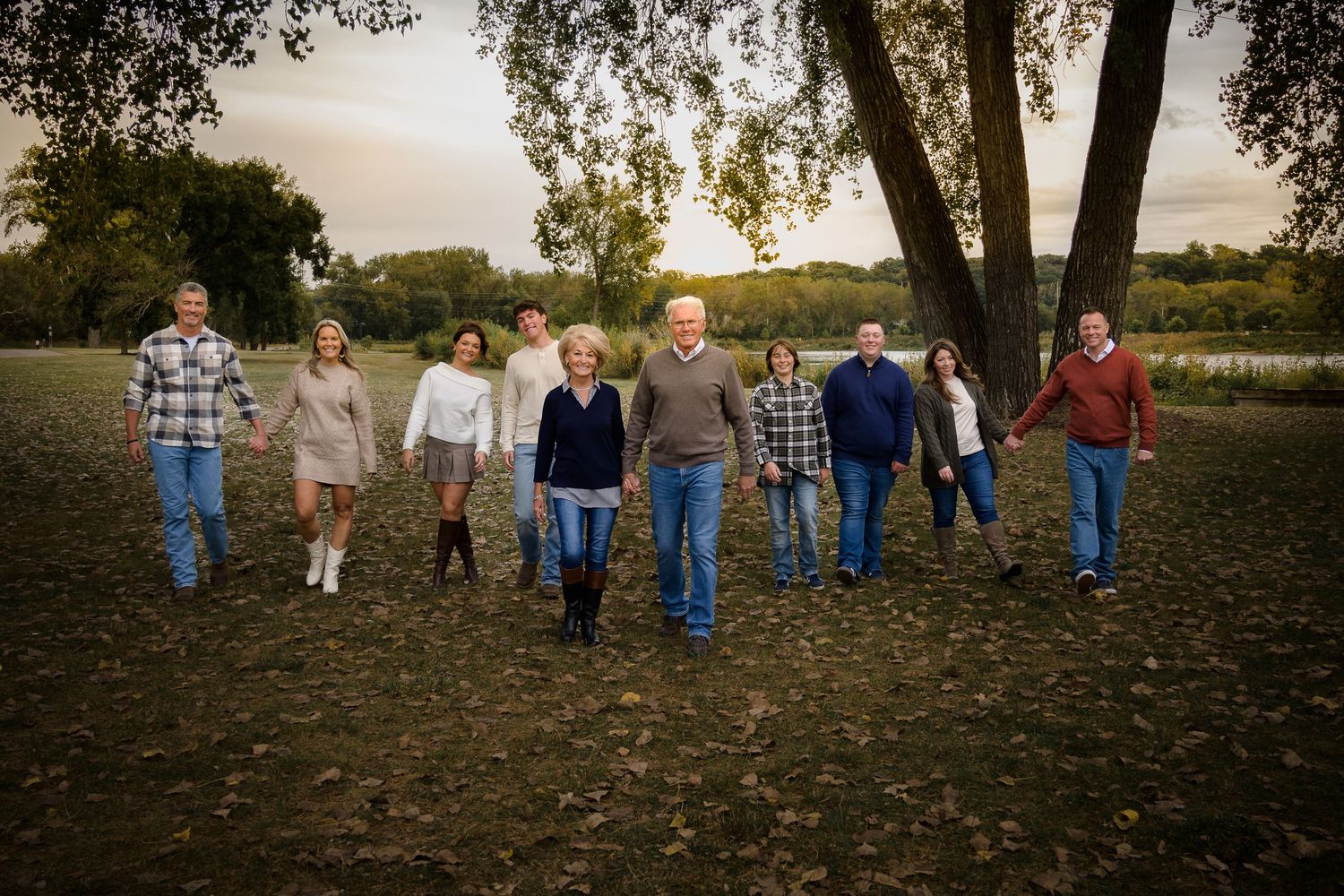 Group of ten family members walking together in an open field at golden hour sunset.