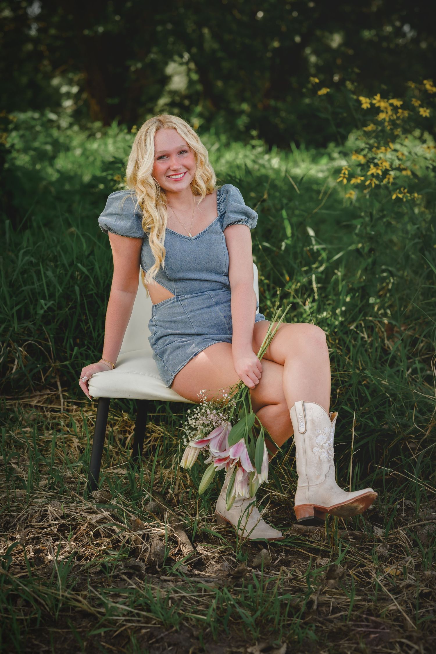 Smiling blond teen girl in gray dress and white cowboy boots sitting in garden chair.