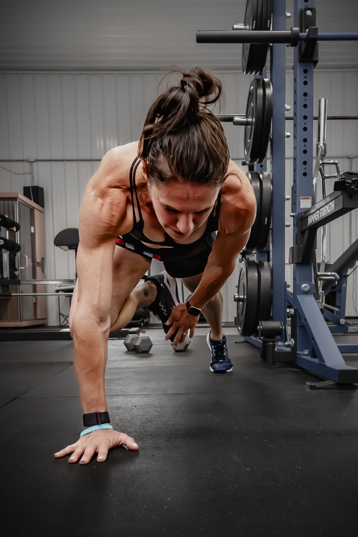 Muscular woman performing a push-up exercise on the floor of a professional gym.