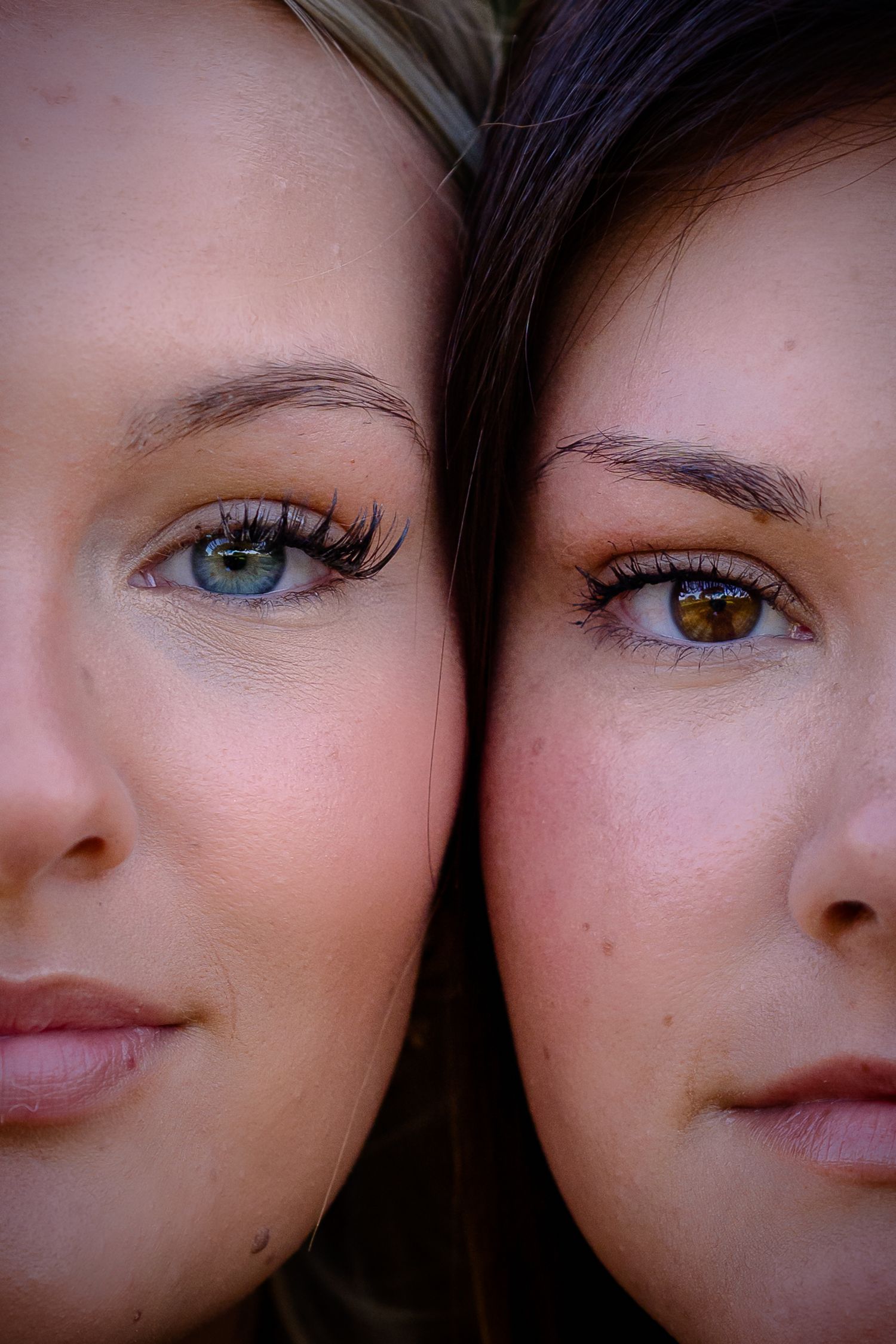 Close-up portrait of two young women with green and hazel eyes, side by side, wearing natural makeup.