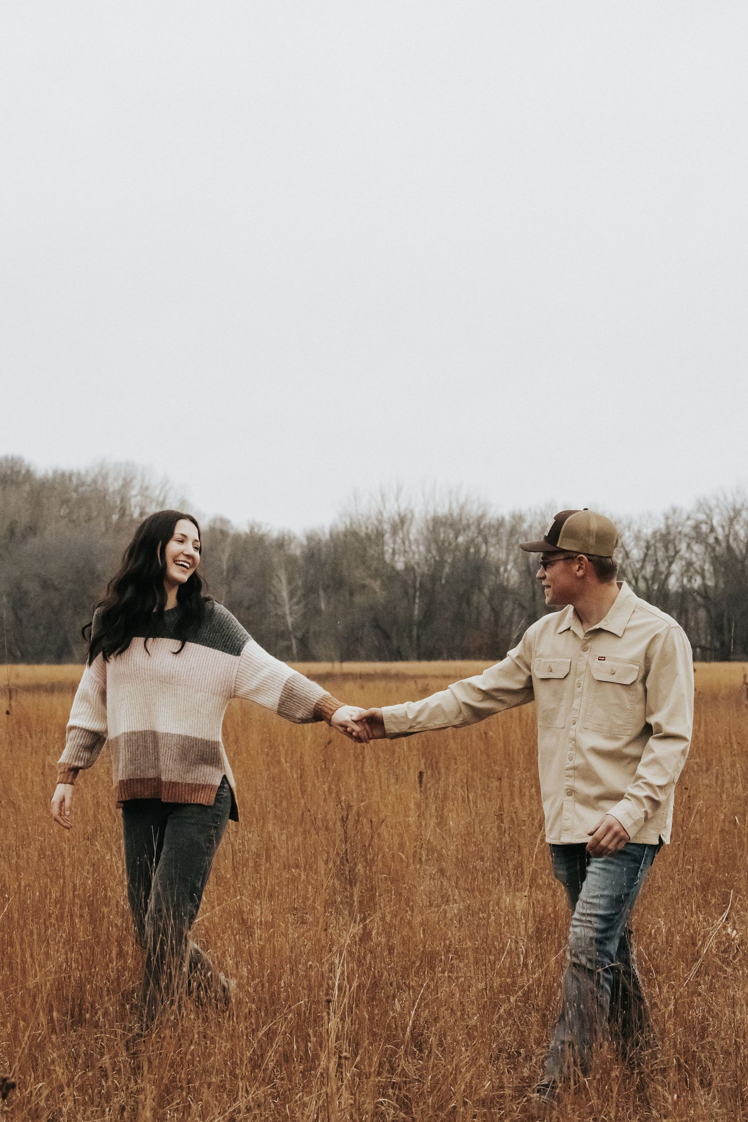 Couple playfully interacting in a golden wheat field during autumn.