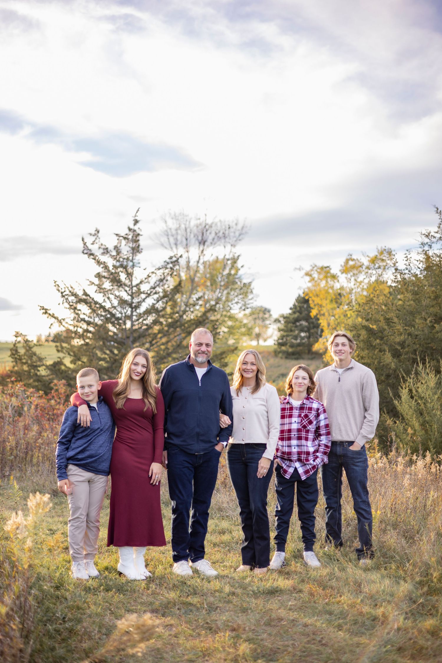 Family group poses together outdoors in casual attire during autumn photo session.
