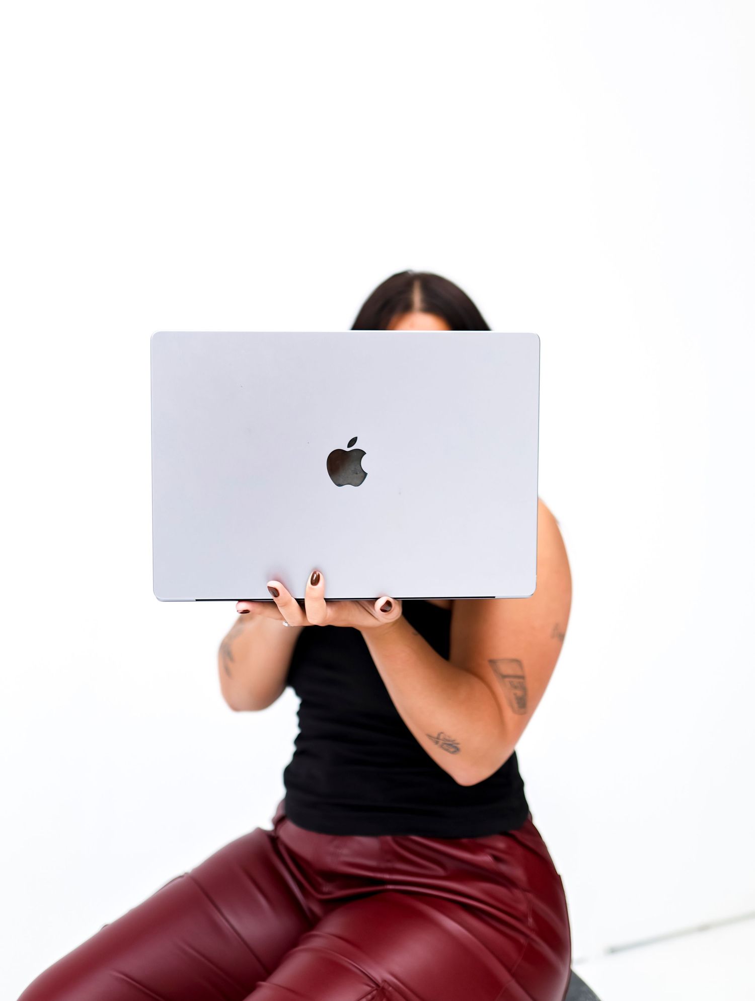 Person in black top holding Apple keyboard while sitting.