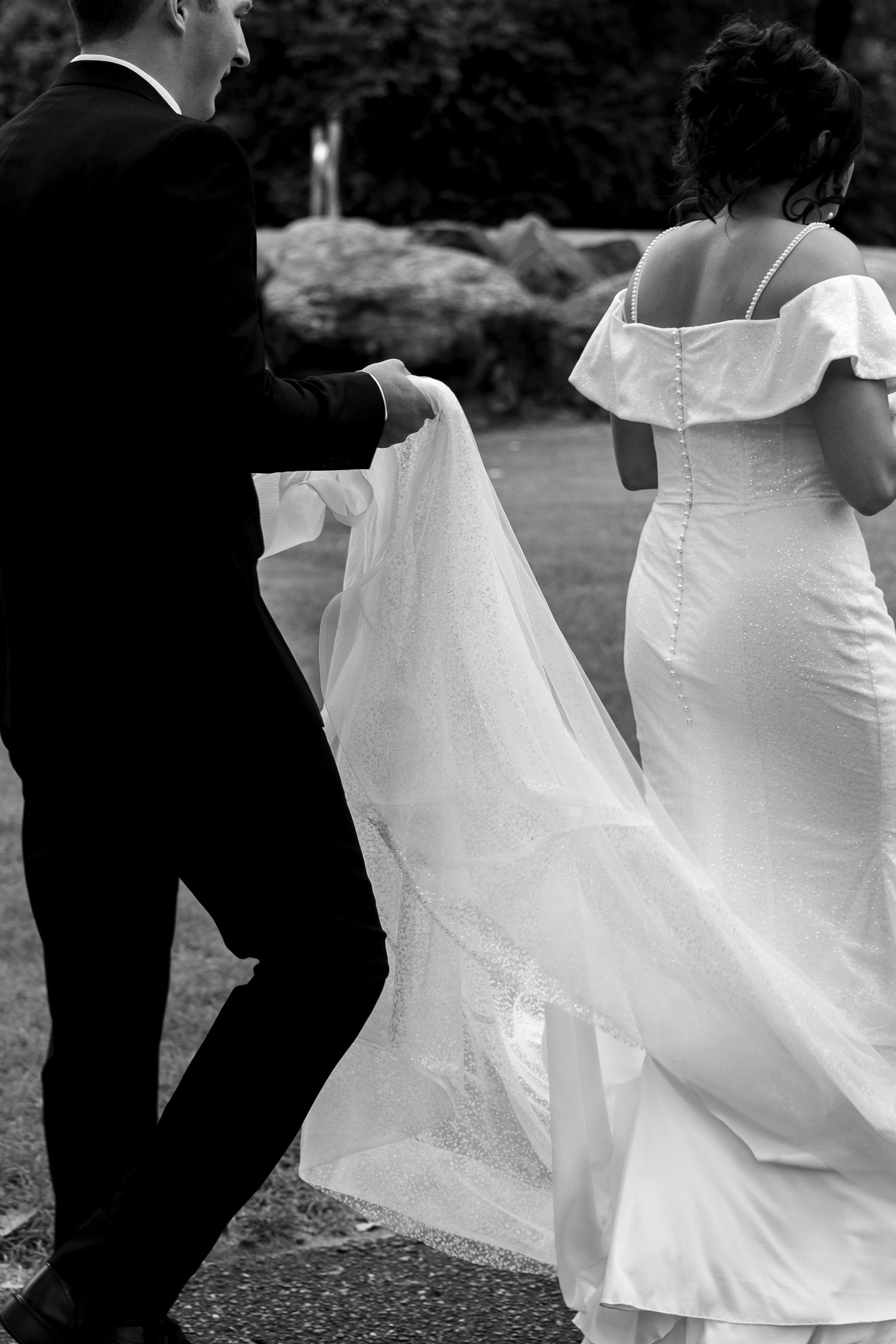 Artistic black and white detail shot of wedding dress movement during an outdoor celebration.