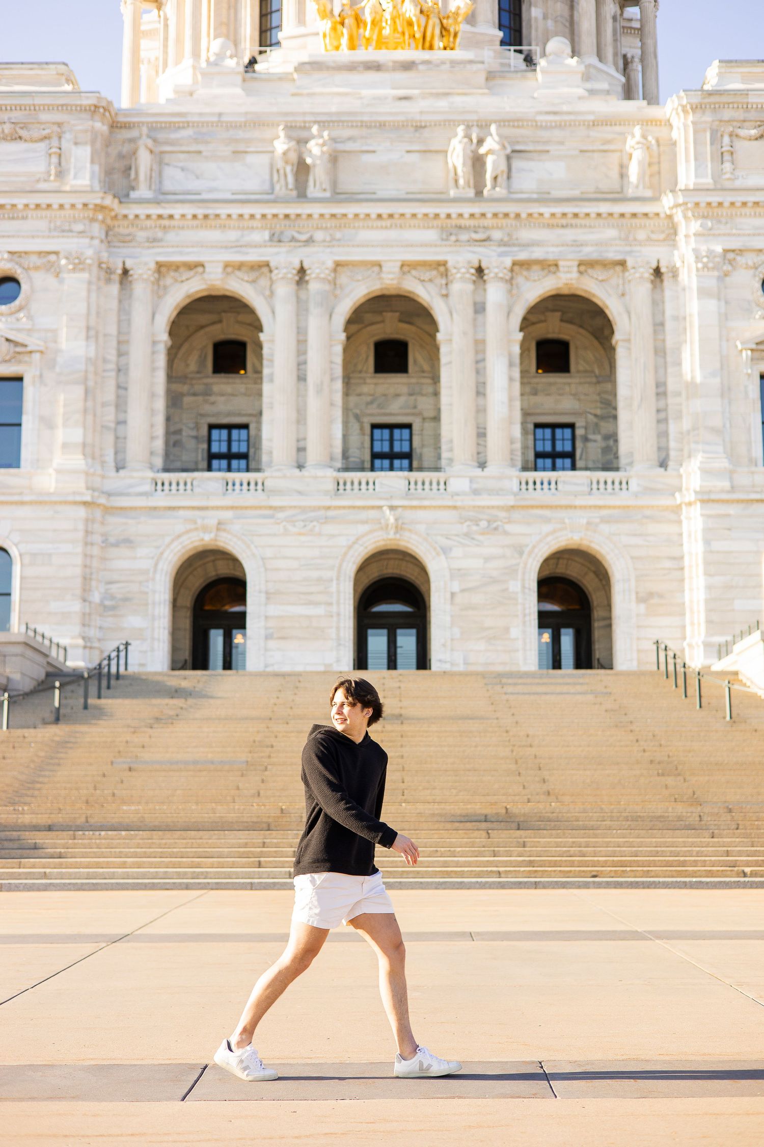 Person in dark sweater running past grand neoclassical government building with ornate architecture.