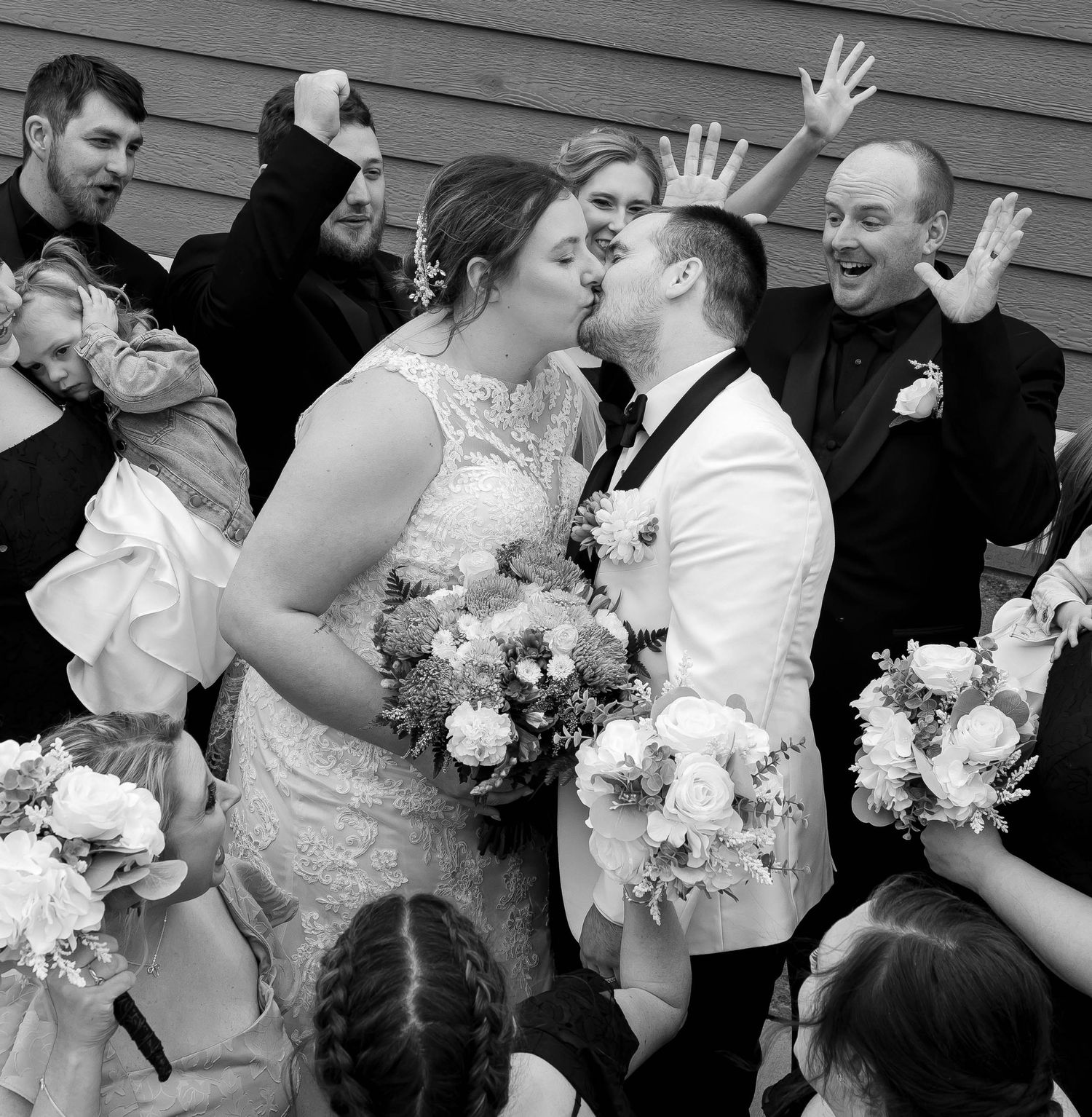 Wedding party celebrates with enthusiasm during outdoor group photo.