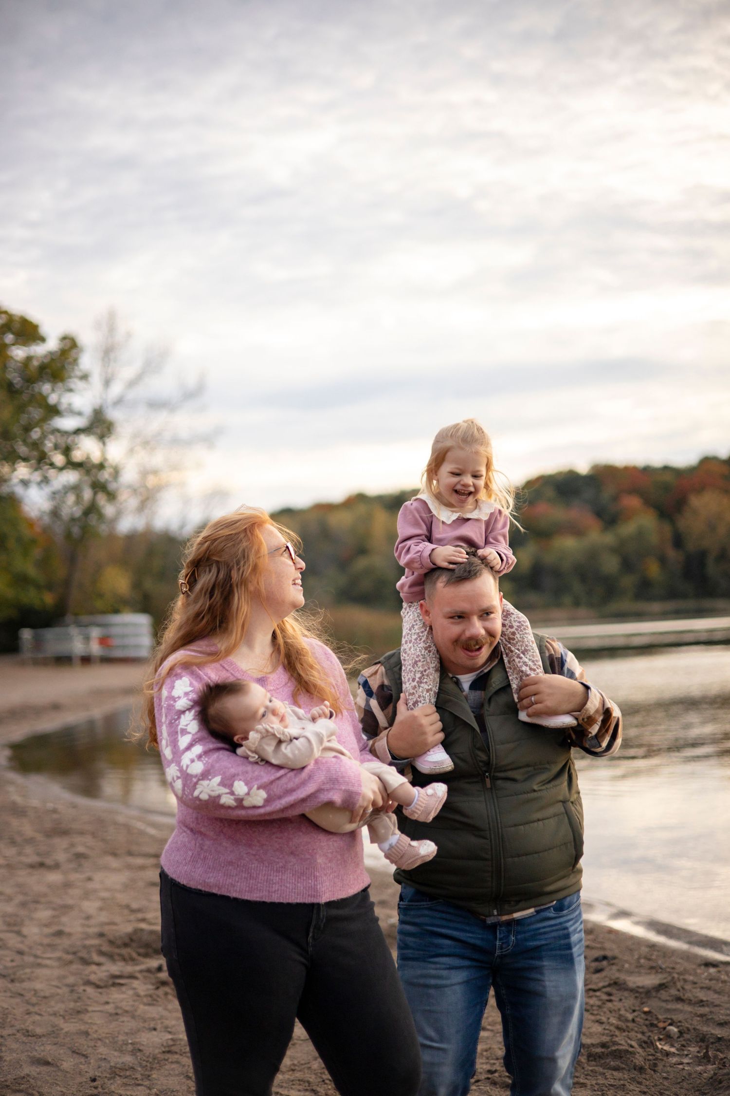 Family enjoying a tender moment together outdoors at sunset by the water.