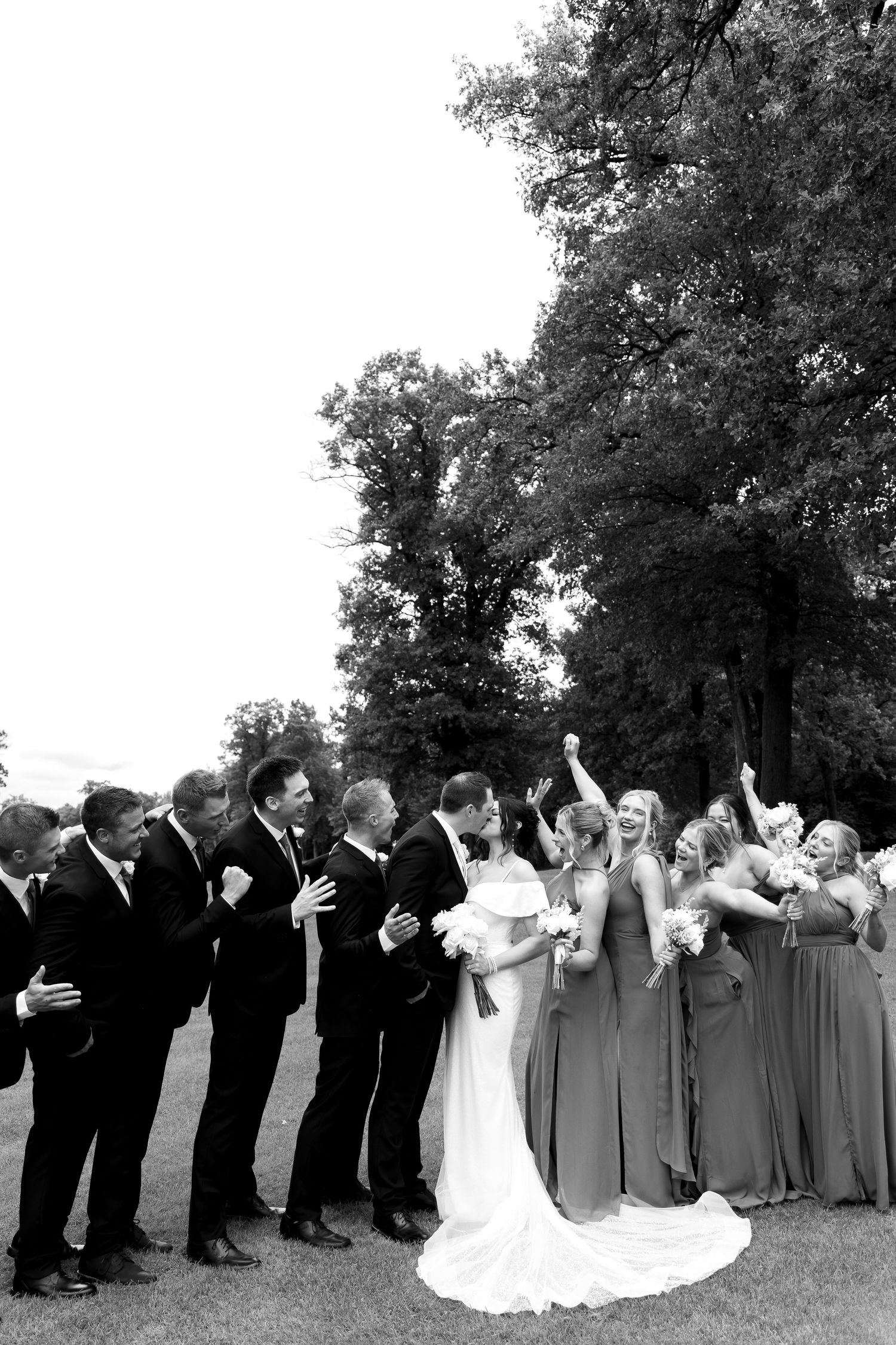 Wedding party poses together outdoors in black and gray formal attire.