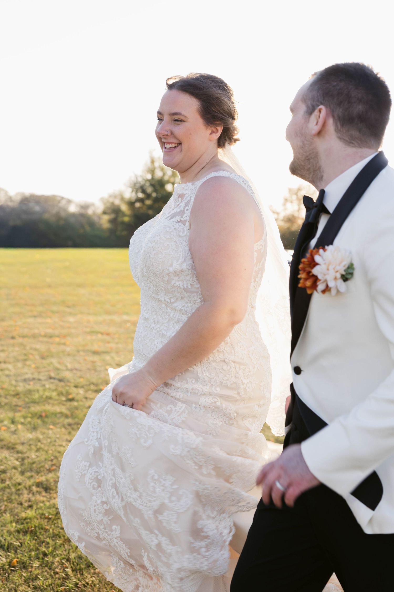Joyful couple walking together at sunset in formal wedding attire.