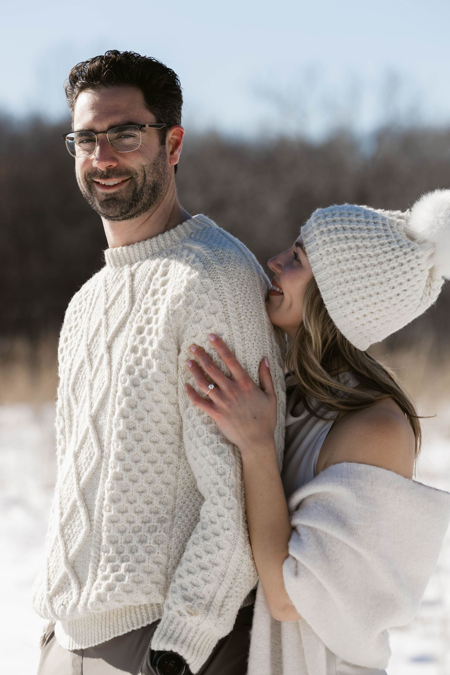A candid winter moment showing affection between a couple wearing cream colored knitwear.