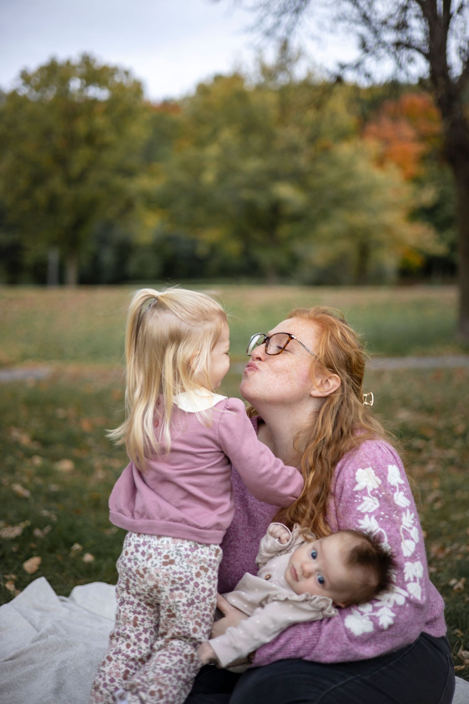 A family shares playful moments on a blanket during a fall photoshoot.
