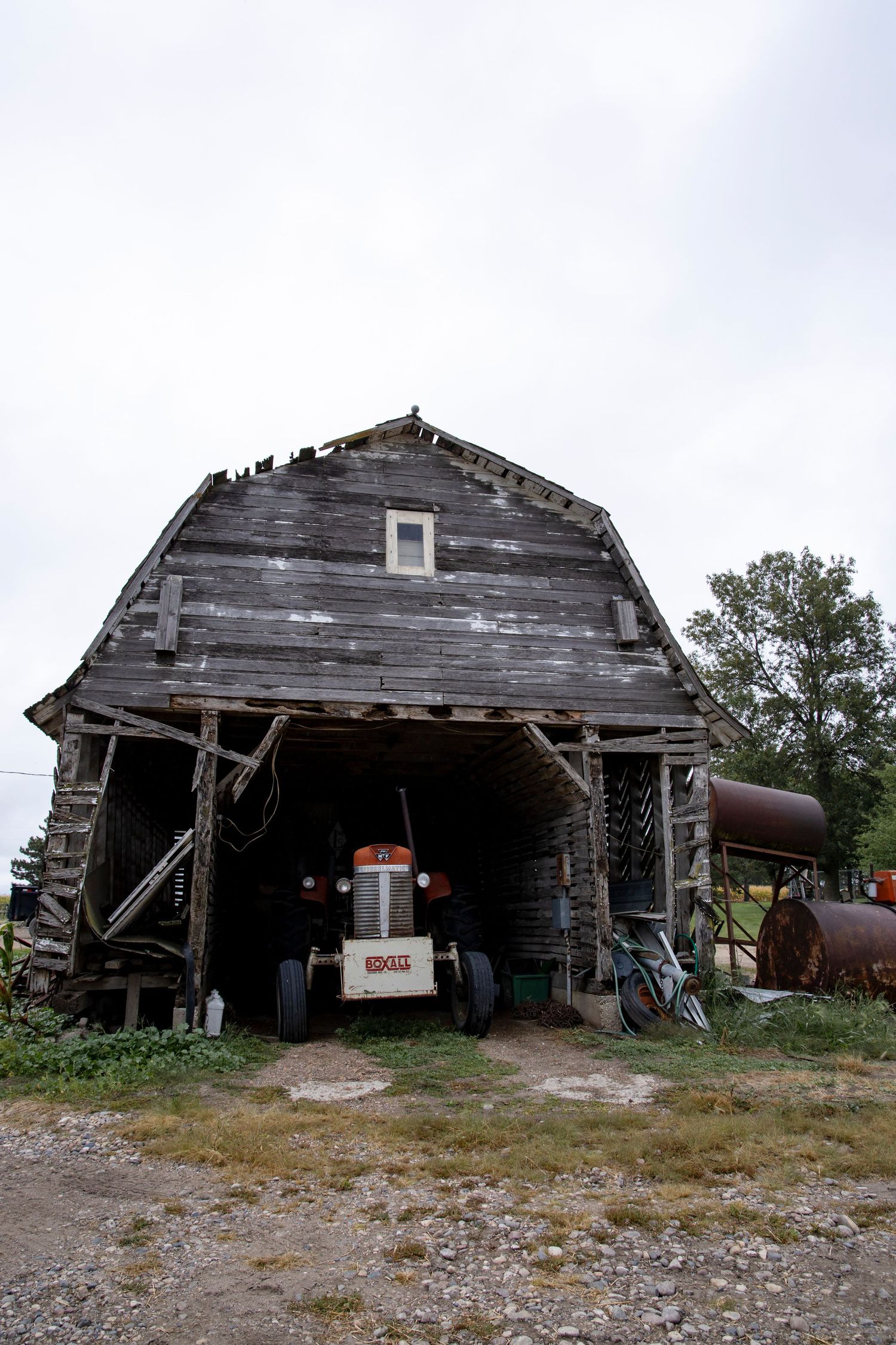 Old weathered barn with vintage tractor visible through the entrance.