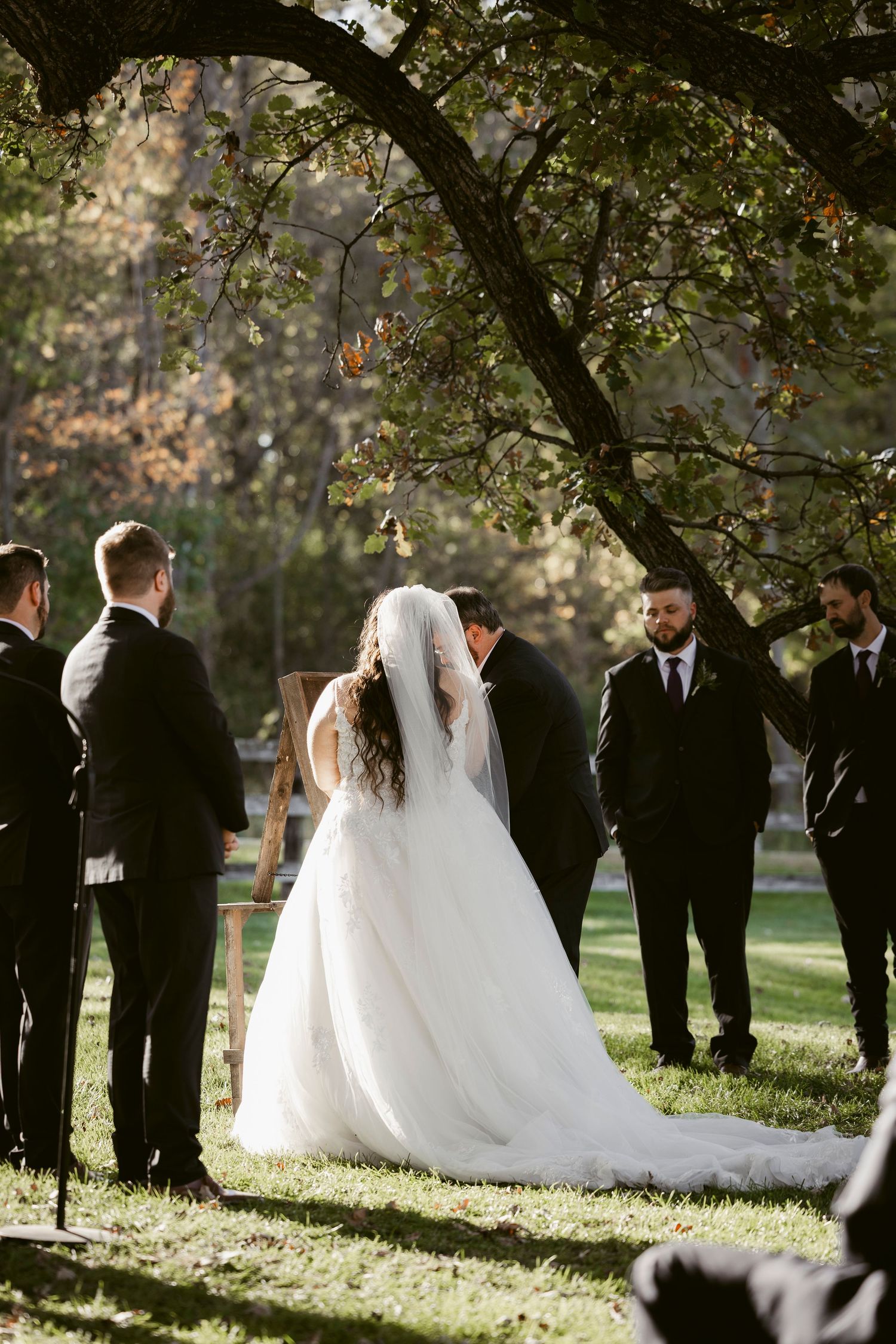 Wedding party gathered under autumn trees during an outdoor ceremony.