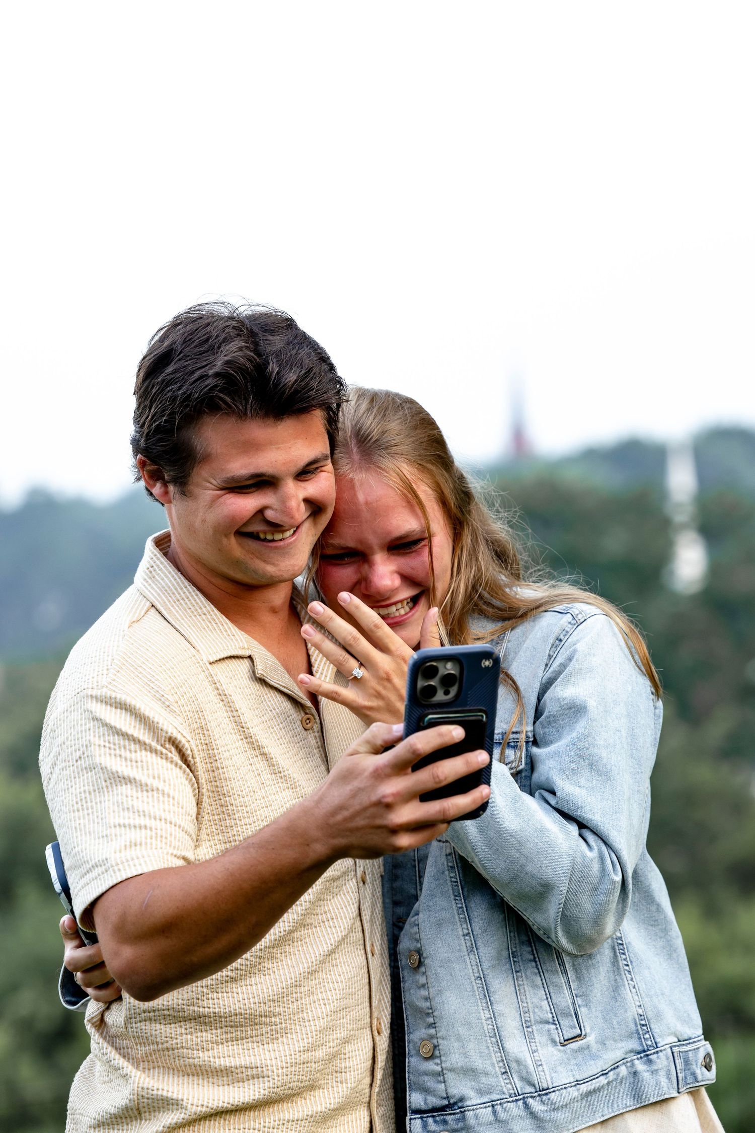 Couple laughing together while looking at a phone outdoors.